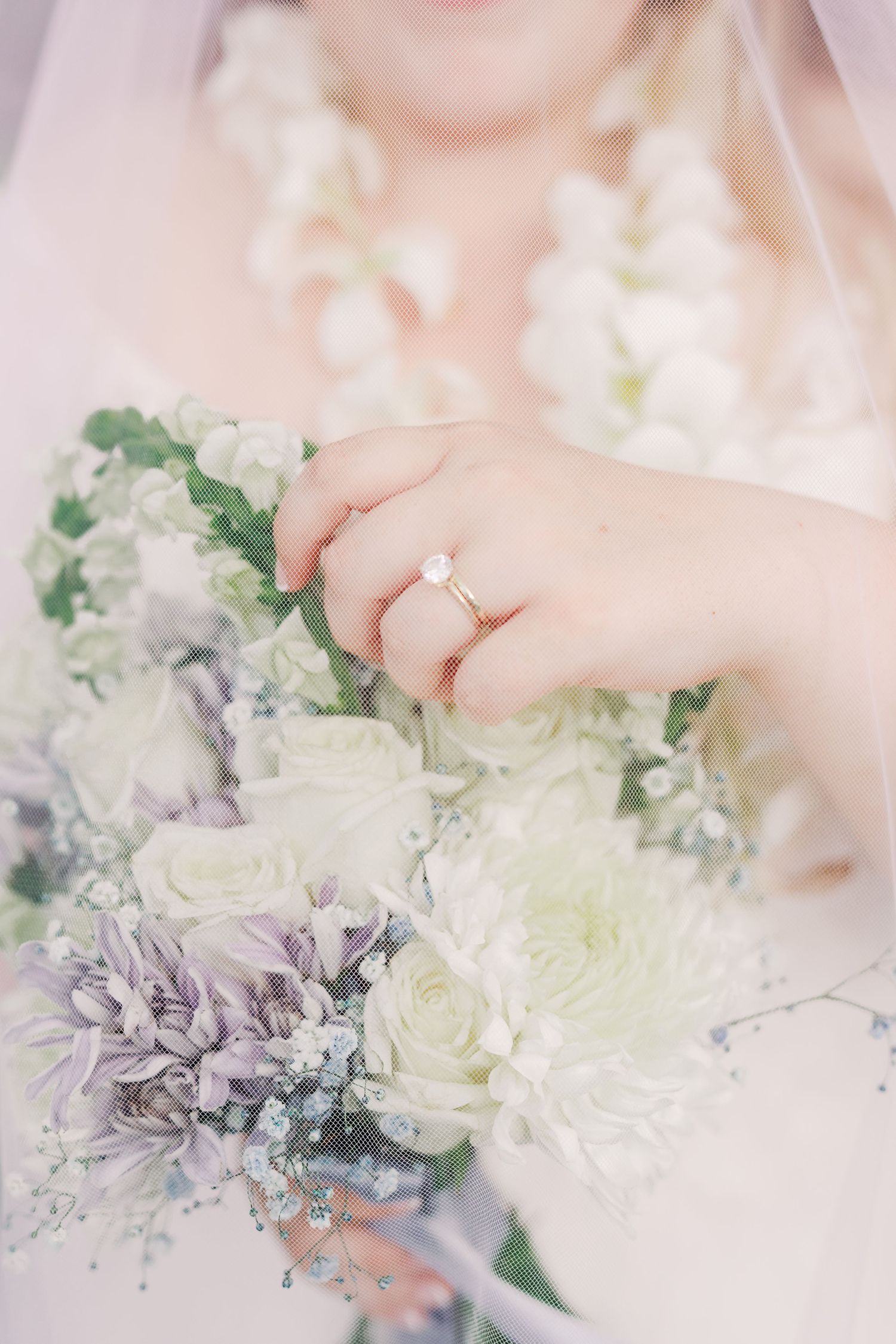 Close-up of engagement ring with white and purple floral bouquet.