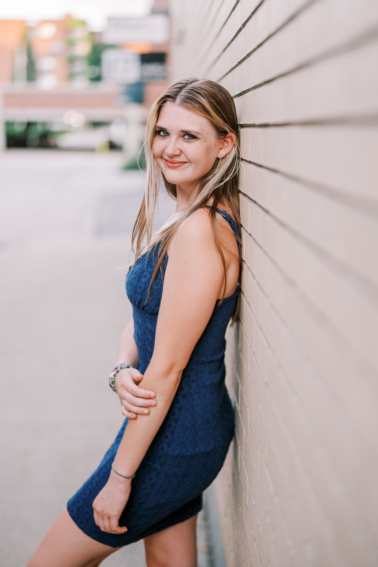 Multiple angles of a casual outdoor photoshoot featuring a sleeveless navy dress against a light colored wall.
