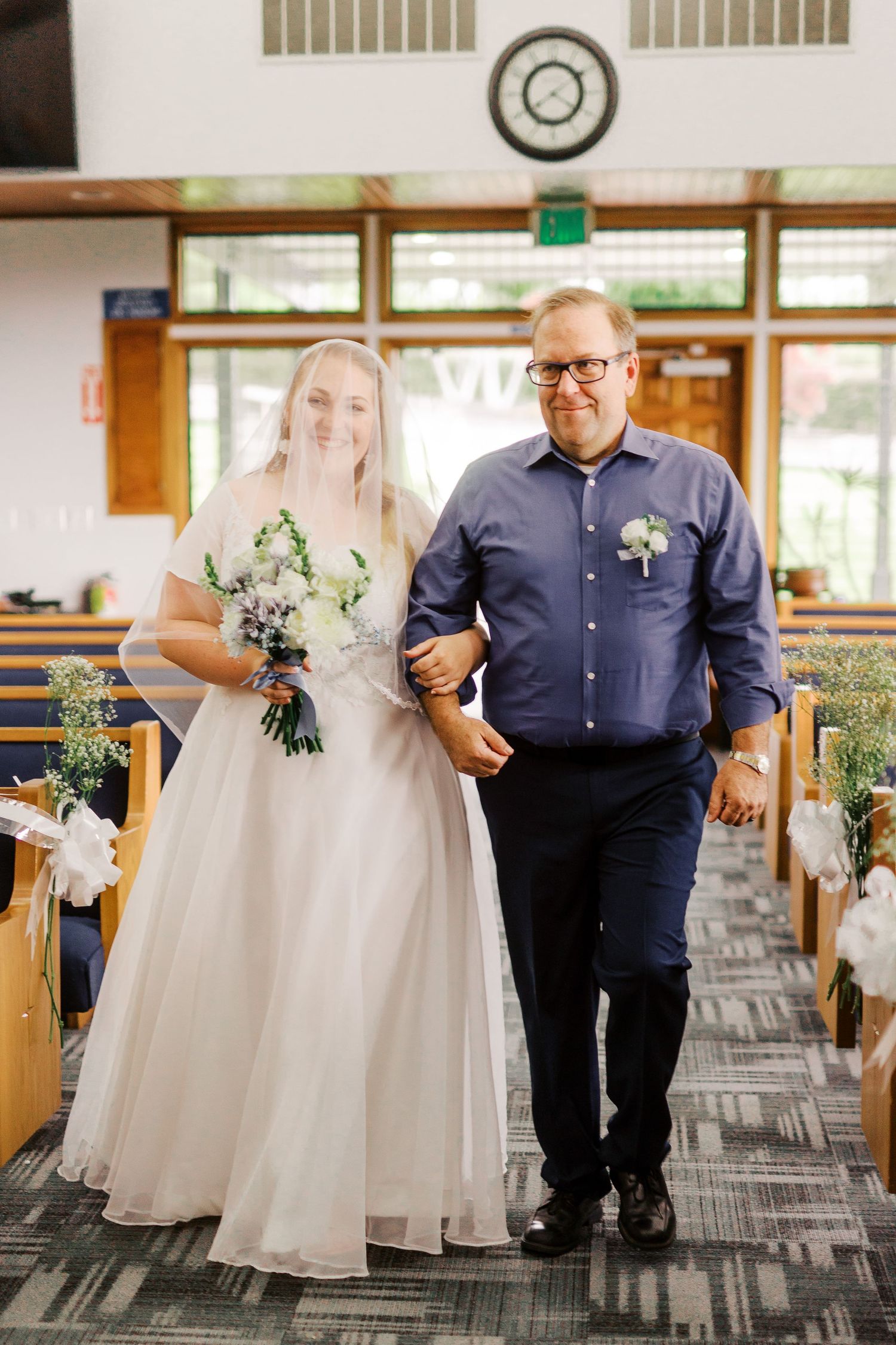 Wedding ceremony processional in a modern chapel interior with wooden beams and natural lighting.
