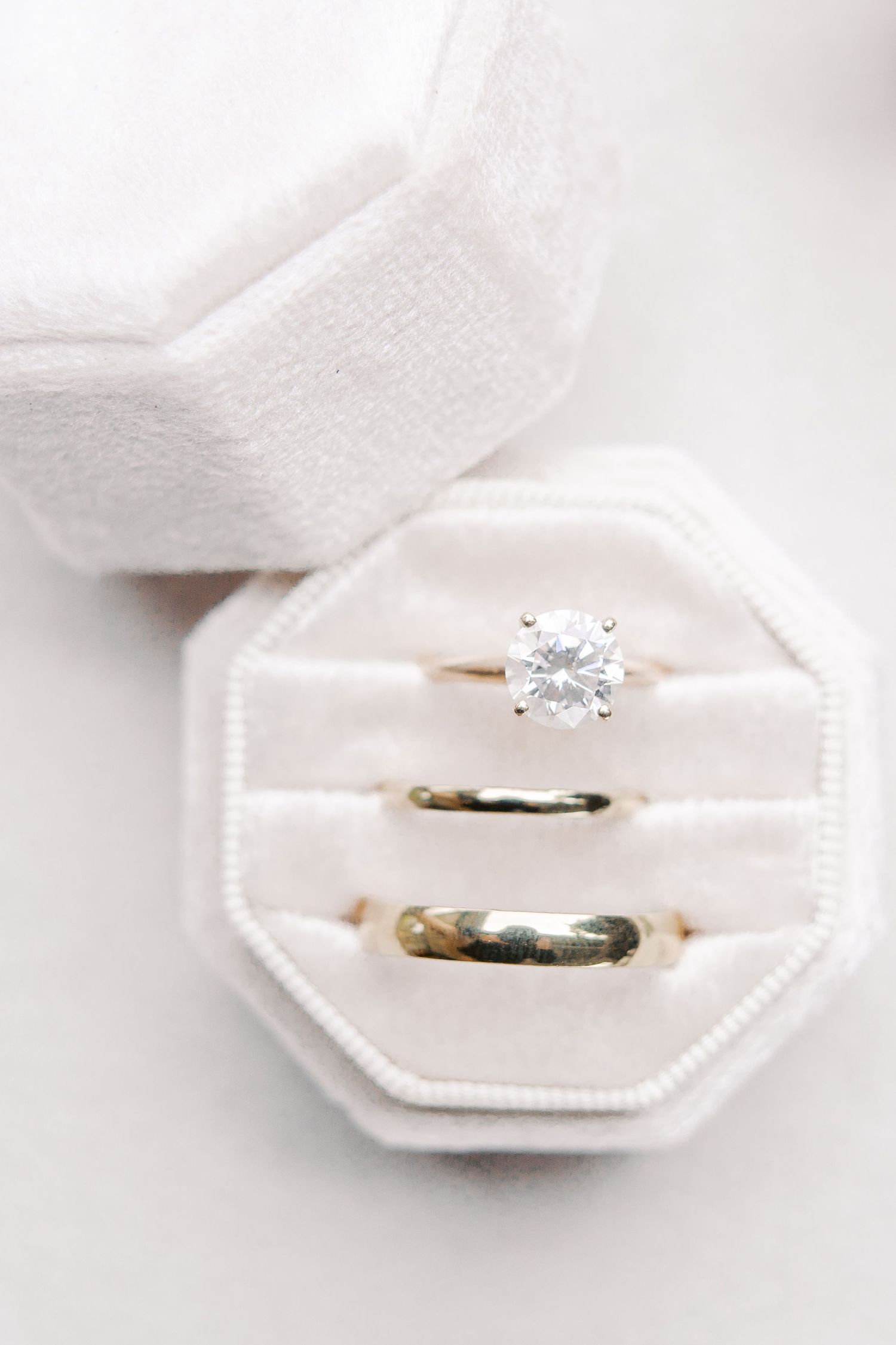 A classic diamond engagement ring and wedding band nestled in a white octagonal ring box.