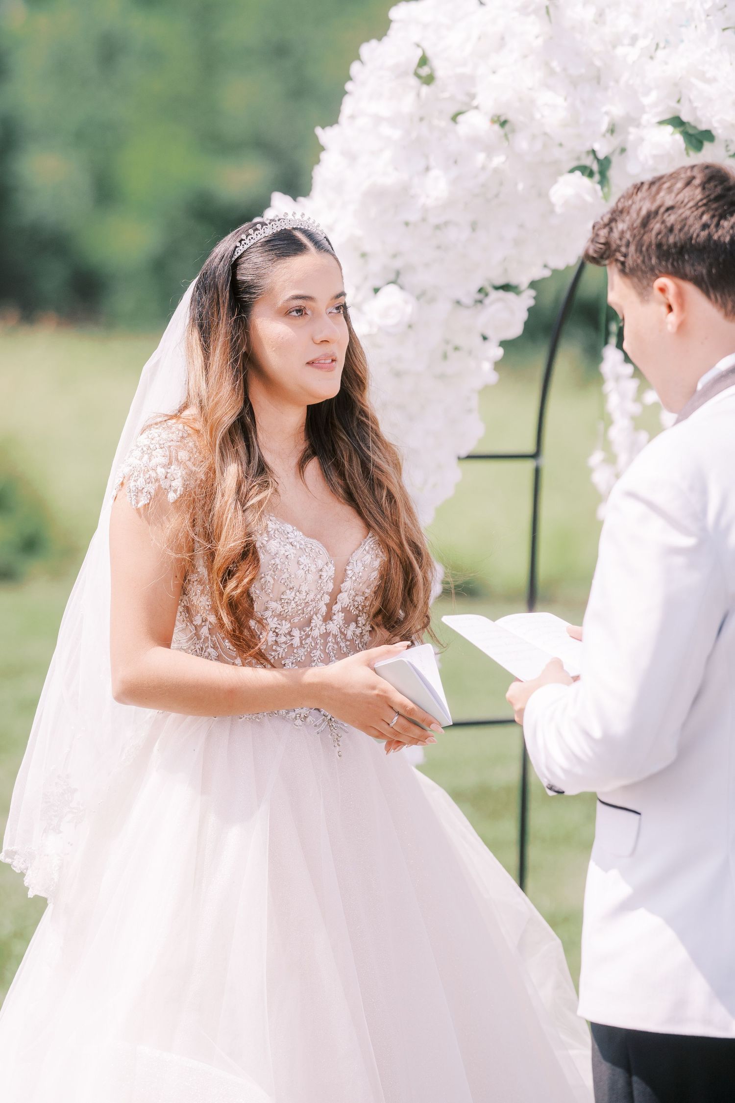 A romantic wedding couple interacts beneath delicate cherry blossoms on a sunny spring day.