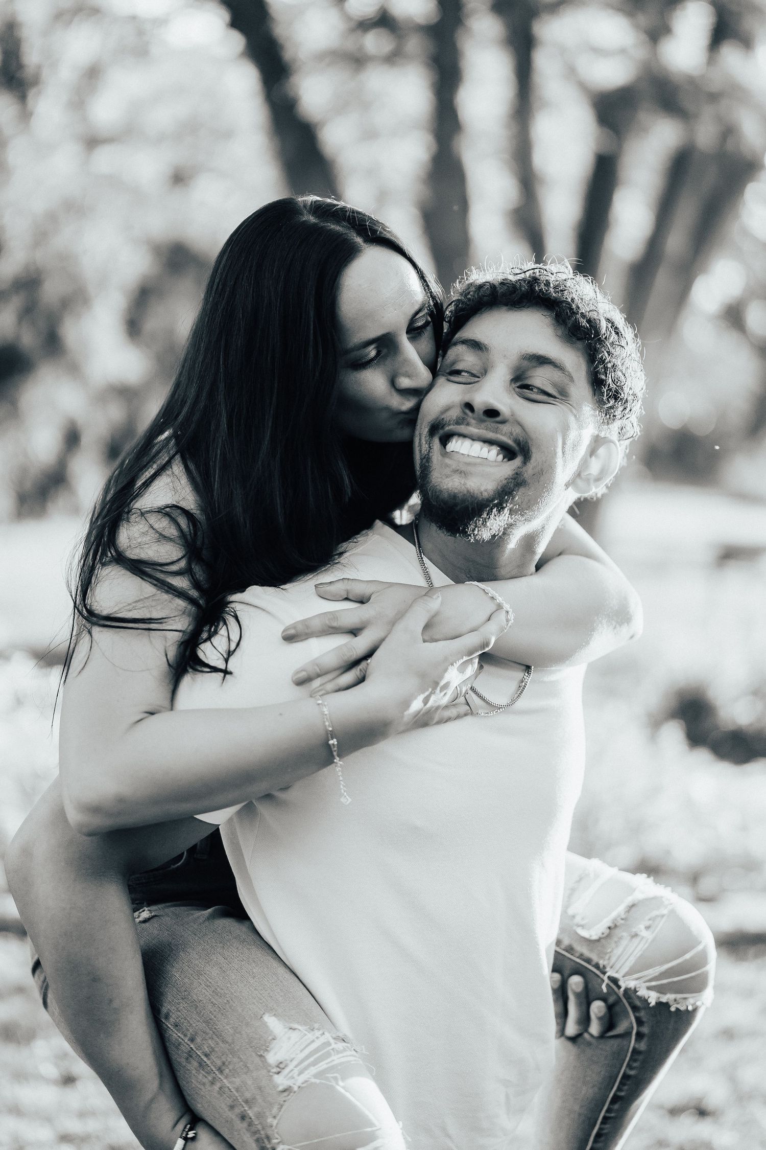 A romantic monochromatic photo series showing two people embracing and sharing joyful moments in natural lighting.
