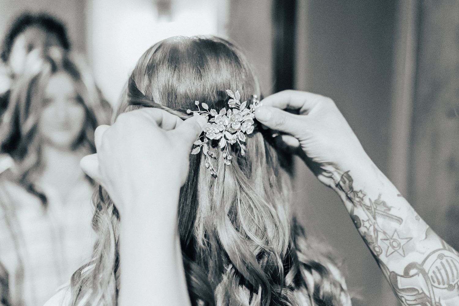 Close-up shot of hands placing delicate floral hair piece on bride's styled hair.
