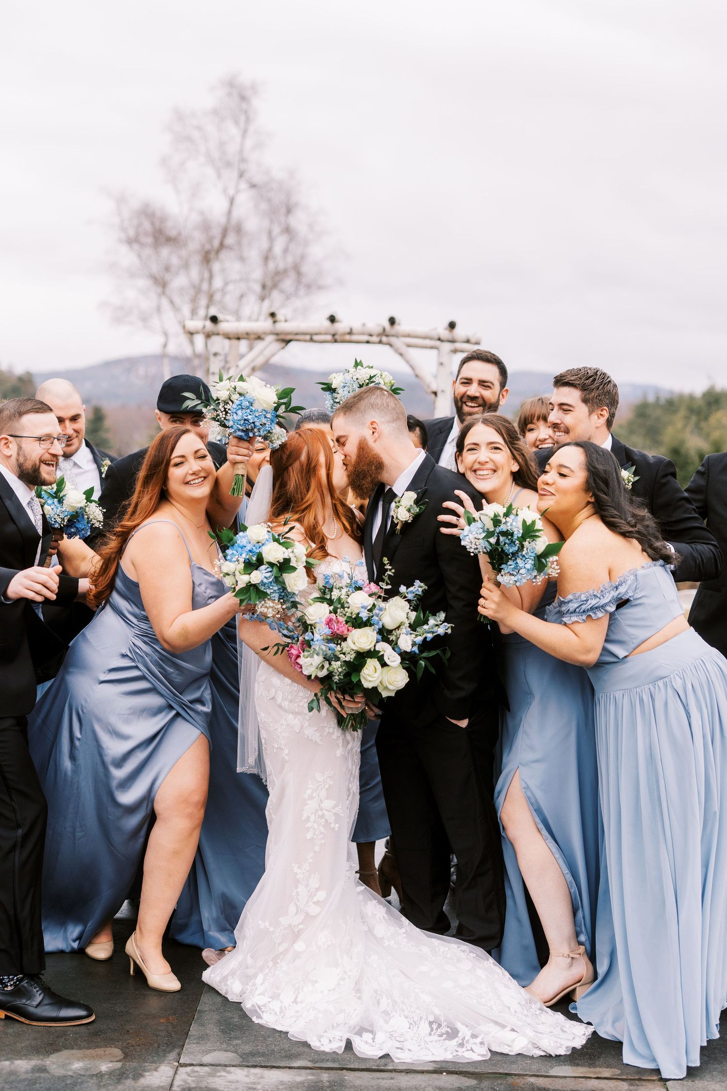 Wedding party celebration with bridesmaids in blue dresses and colorful bouquets.