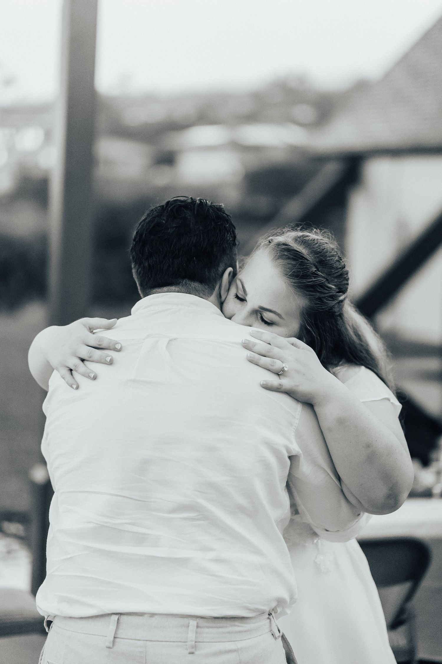 Black and white photograph of a tender embrace between newlyweds during their wedding celebration.