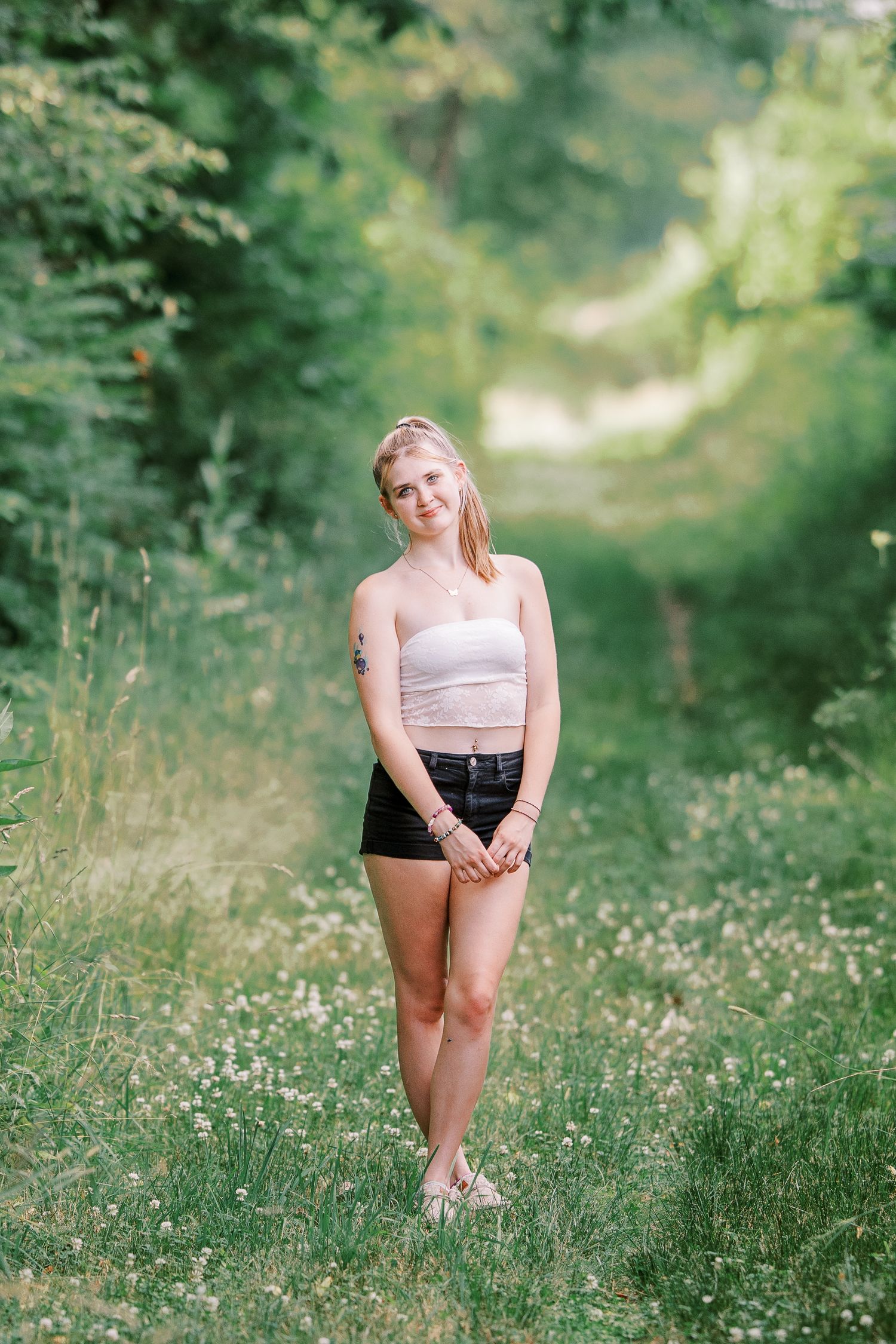 Summer portrait in a sunlit forest path with blooming wildflowers and lush greenery in the background.