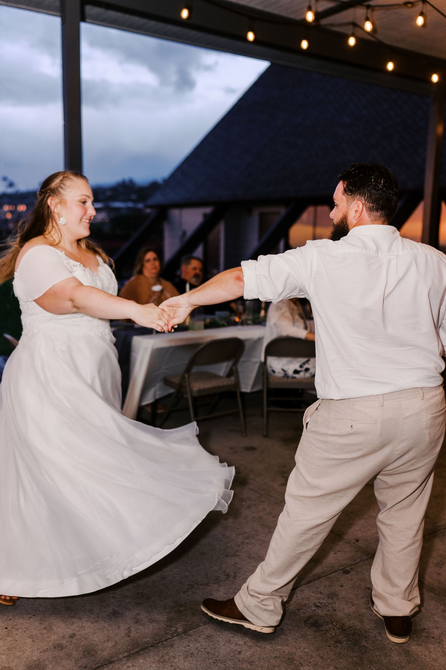 A joyful wedding dance captured during an evening reception under string lights.