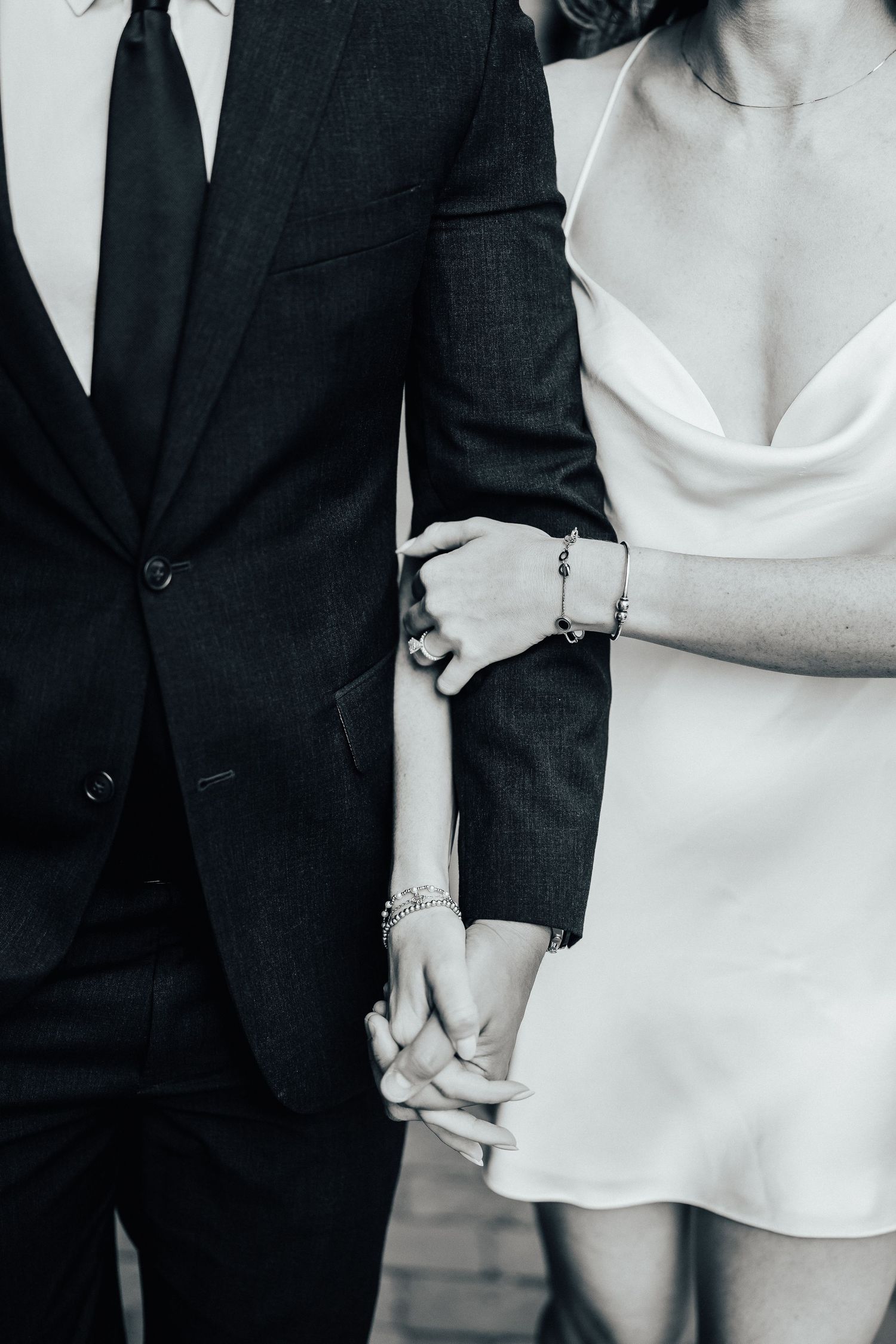 Black and white image showing contrasting formal attire with a dark suit jacket next to a light-colored dress.