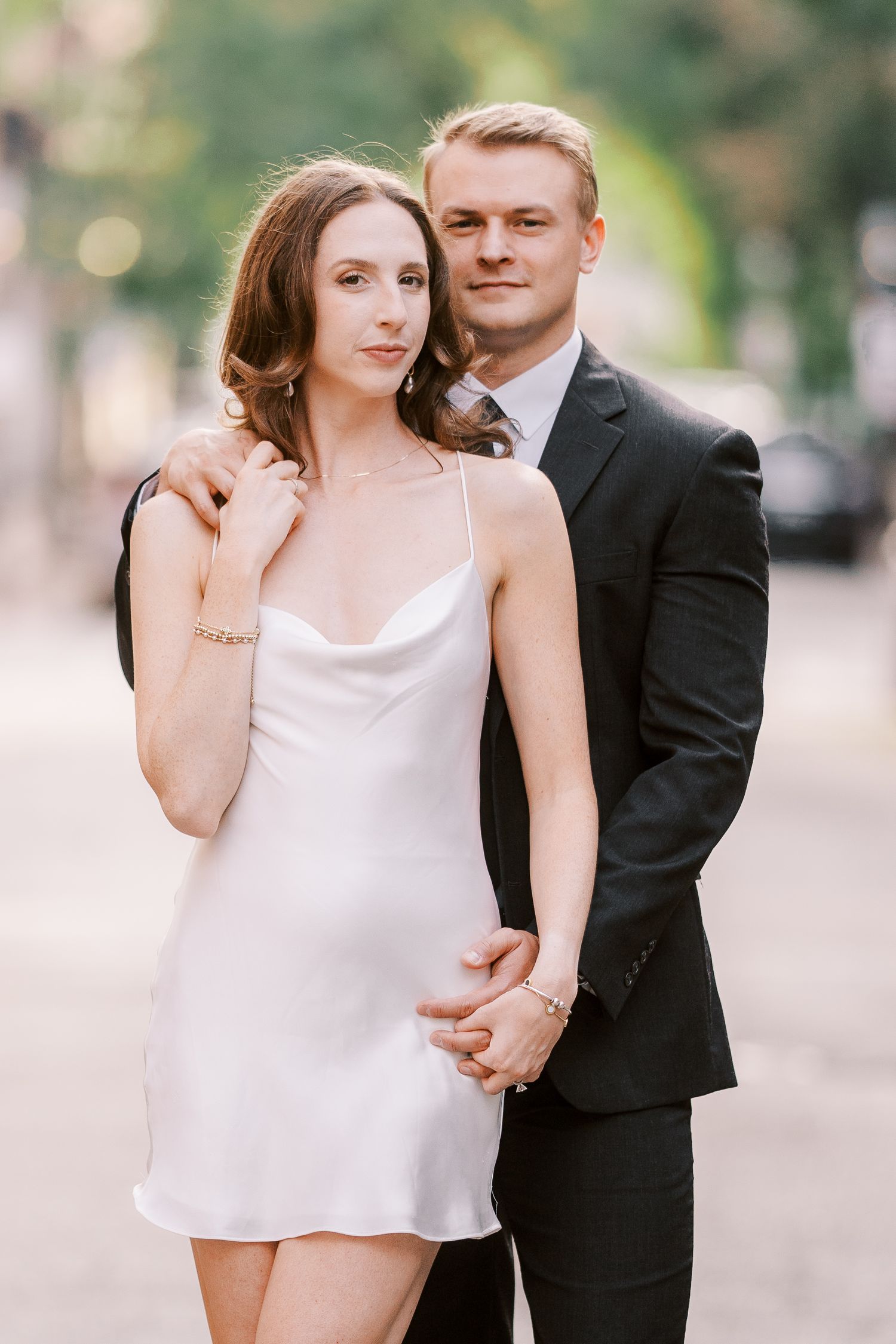 A couple shares intimate moments in a romantic outdoor photoshoot with a white dress and black suit.