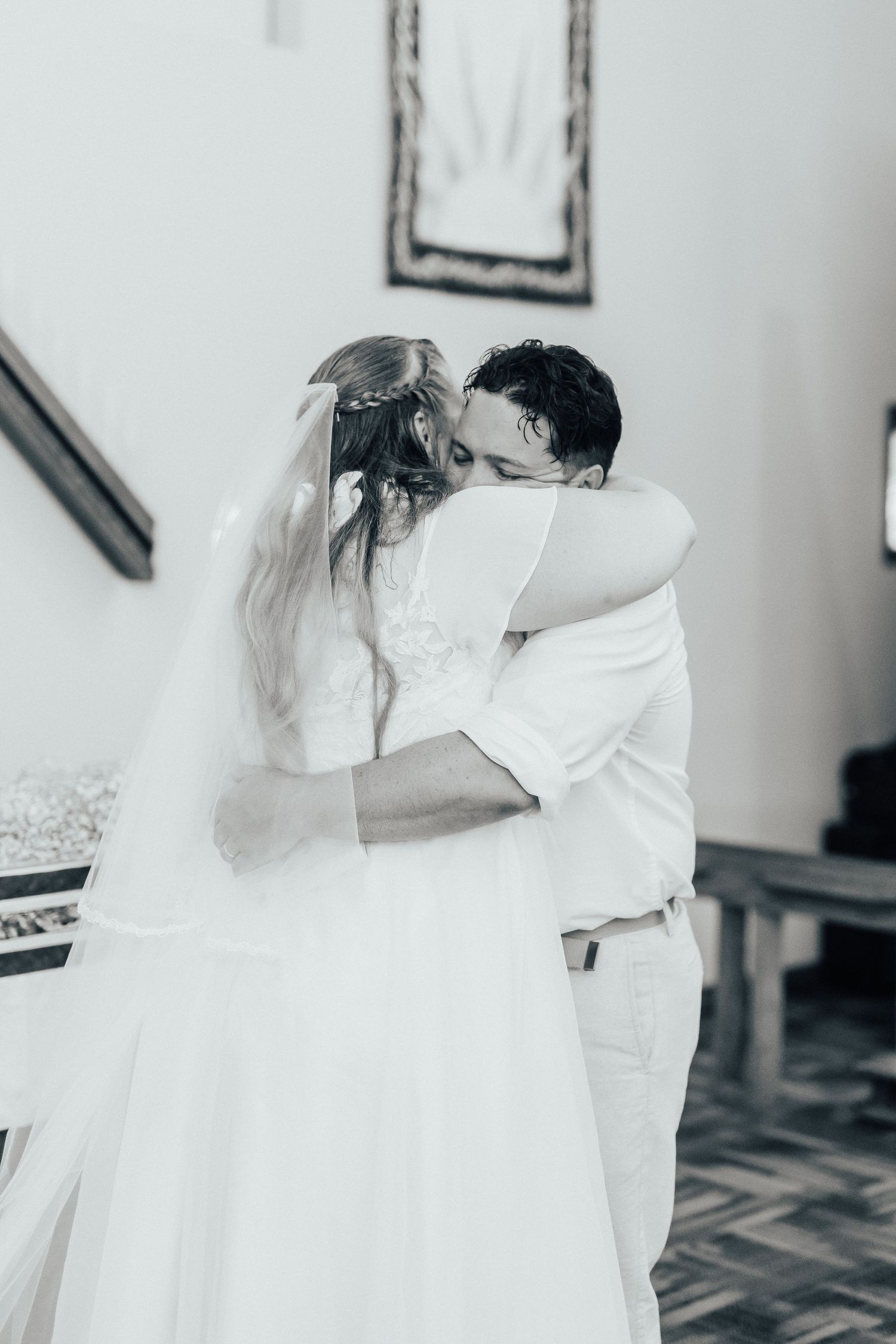A romantic wedding moment captured in black and white as a couple embraces in their white attire.