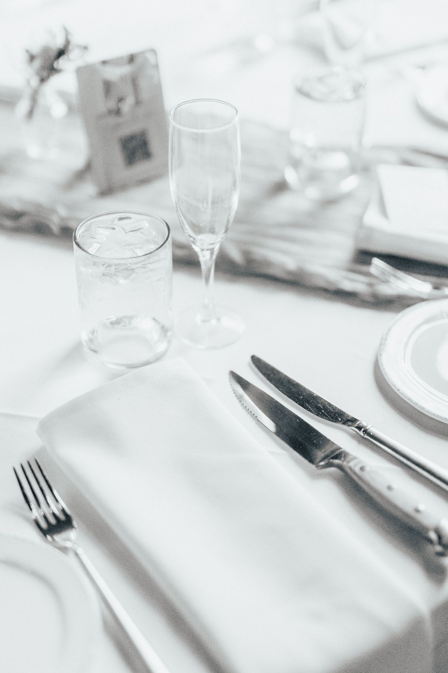Elegant table setting with white linens, silverware, and glassware for a formal wedding reception.