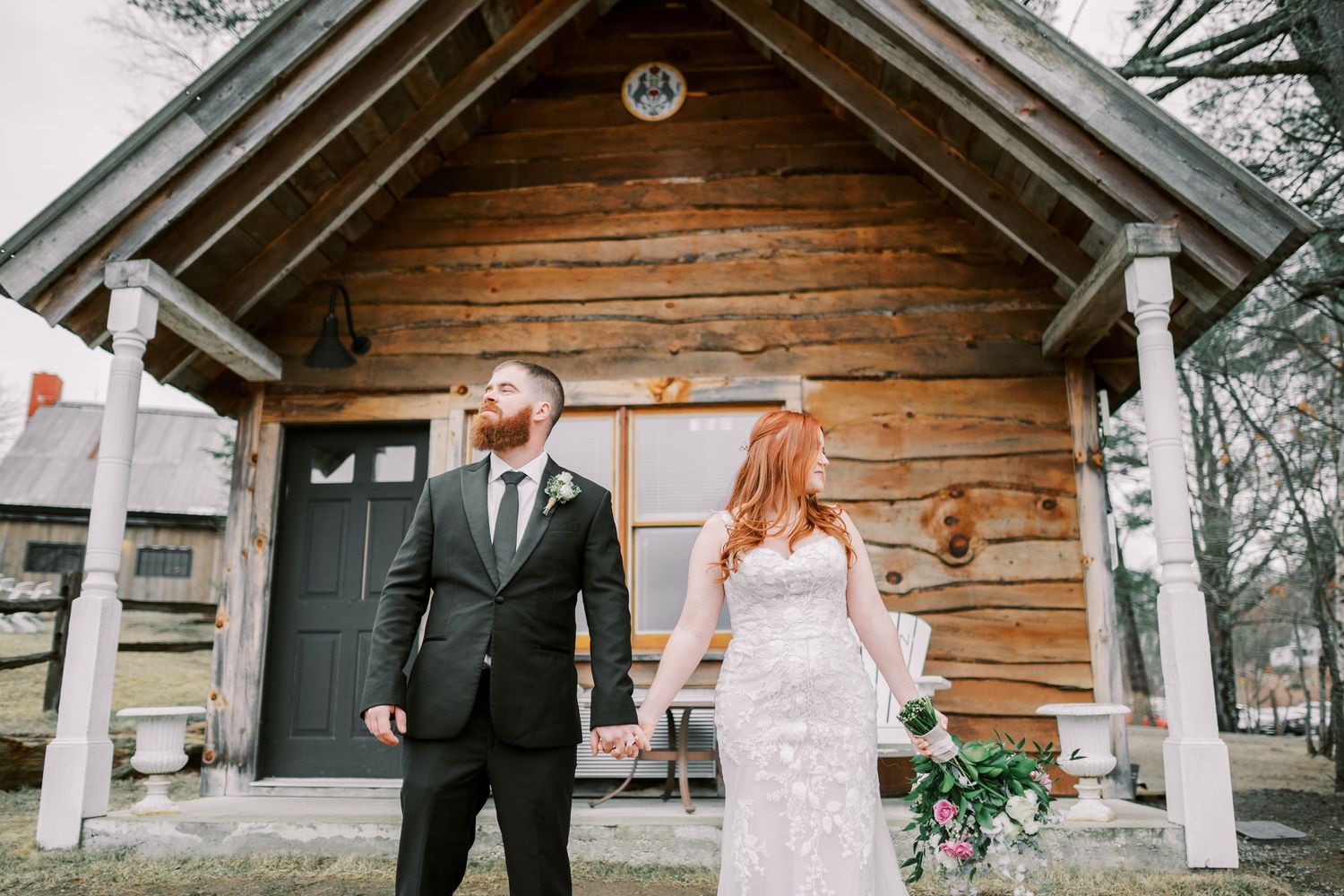 A couple poses in front of a rustic wooden chapel during their wedding day.