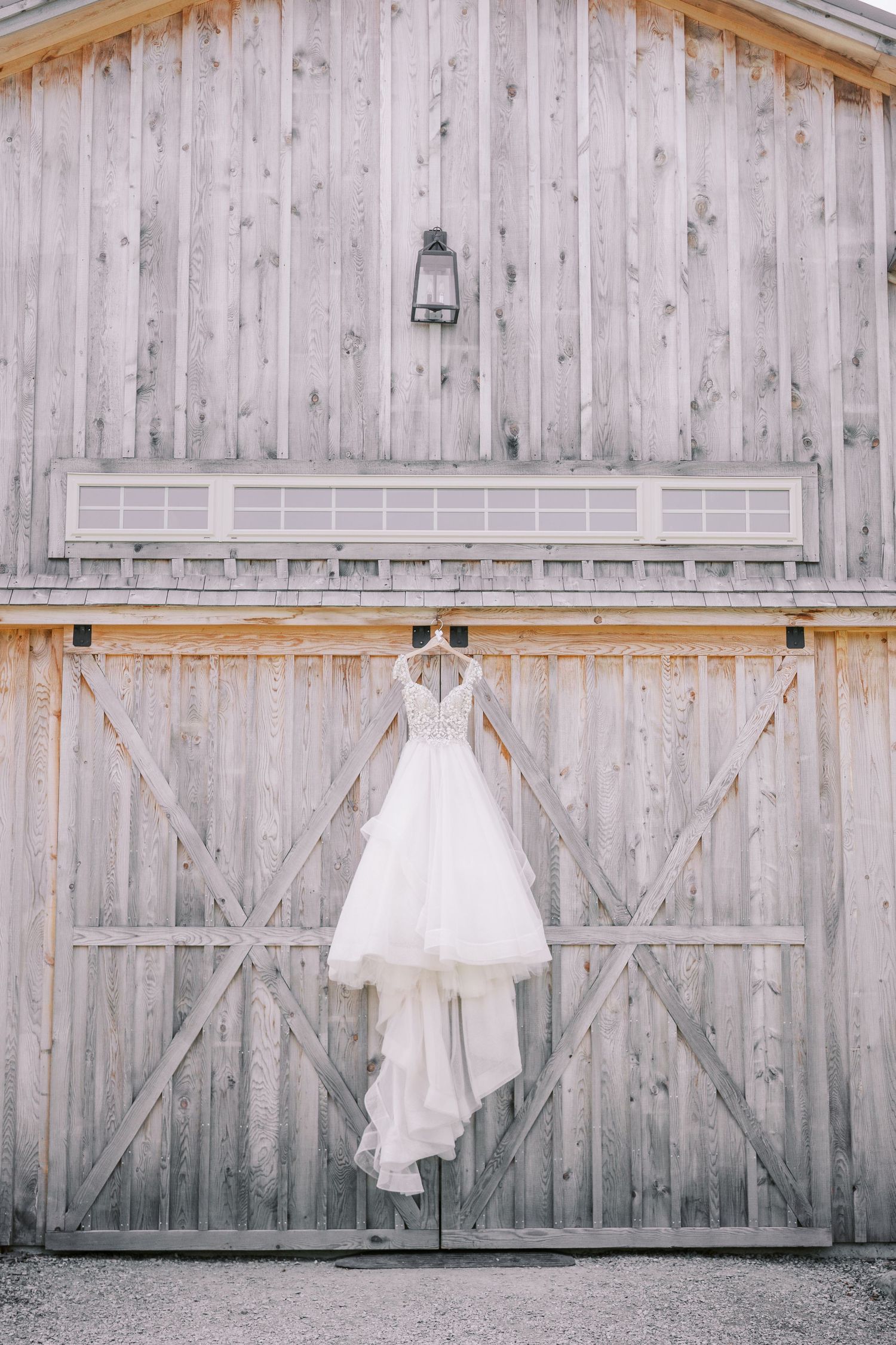 Elegant white wedding dress hanging against rustic barn wood wall in four sequential minimalist photographs.
