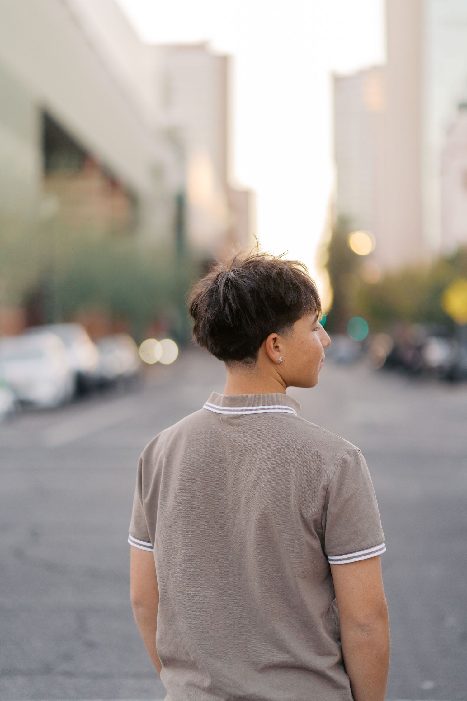 Five sequential shots of a person in a grey top walking on a city street during sunset.