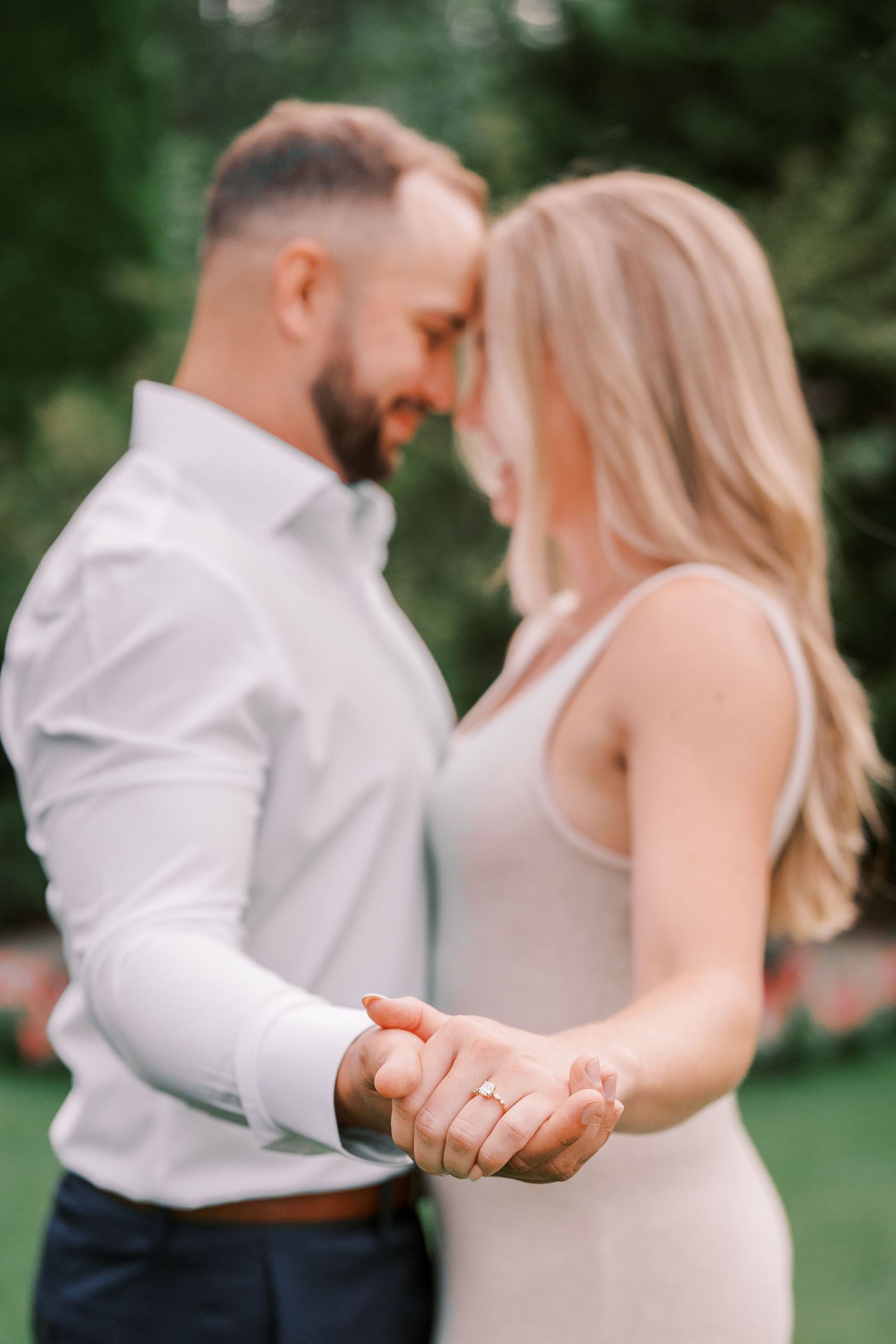 Couple sharing tender moment while dancing outdoors in elegant attire.