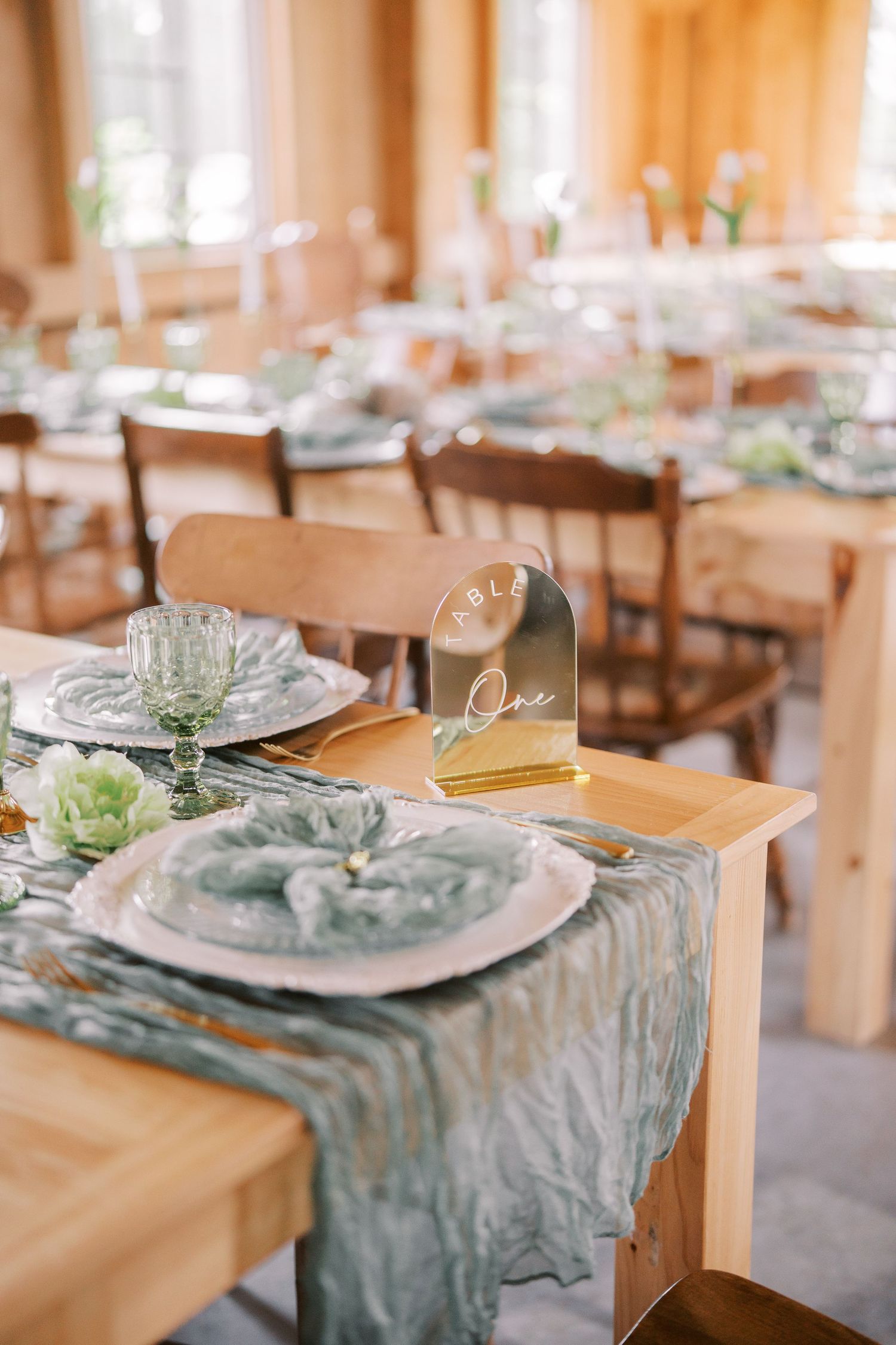 Elegant table setting with dusty blue runners, crystal glasses and white plates at a wedding reception.