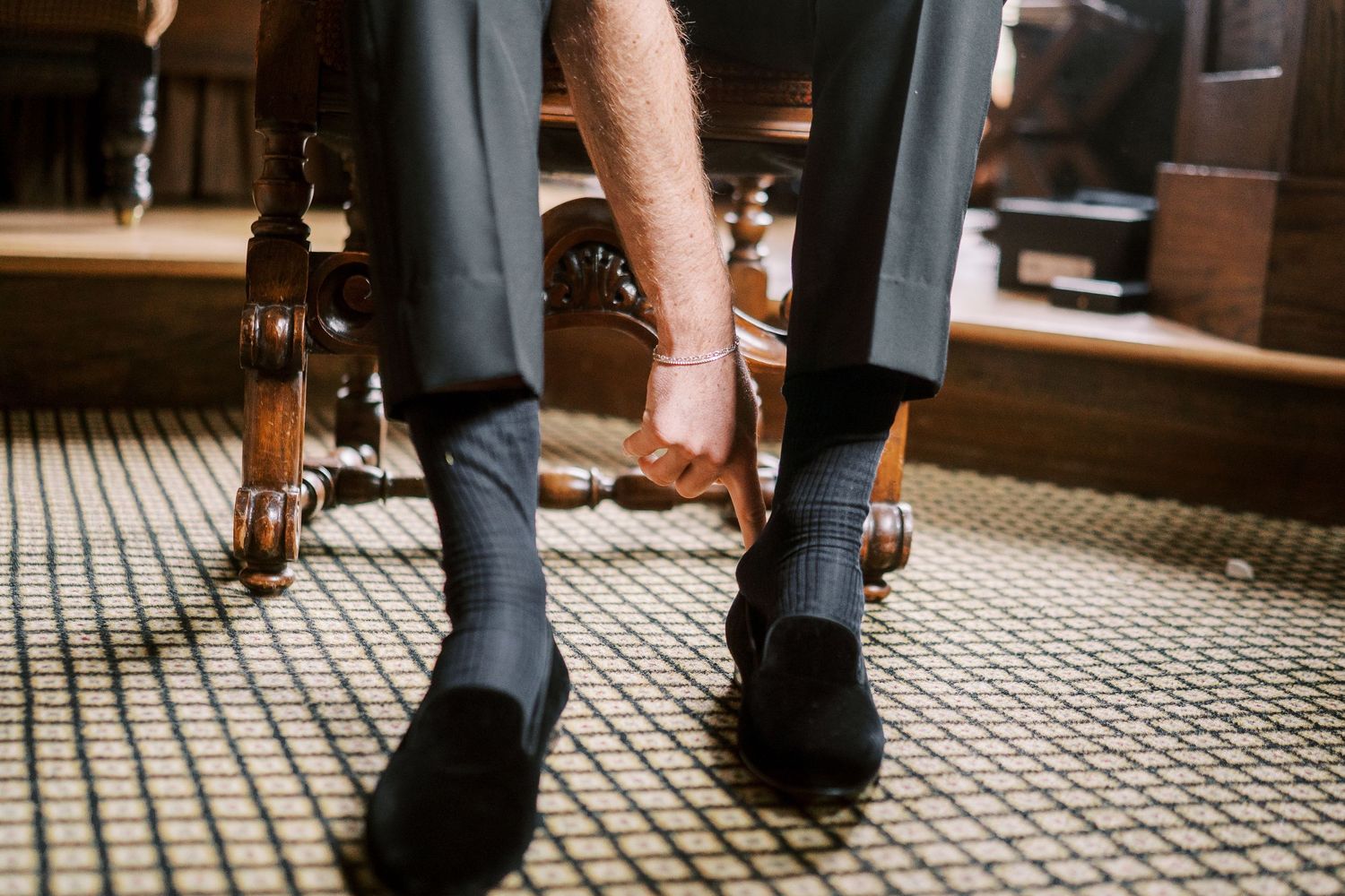 Close-up view of multiple pairs of dress shoes walking on a tiled mosaic floor in an elegant indoor space.