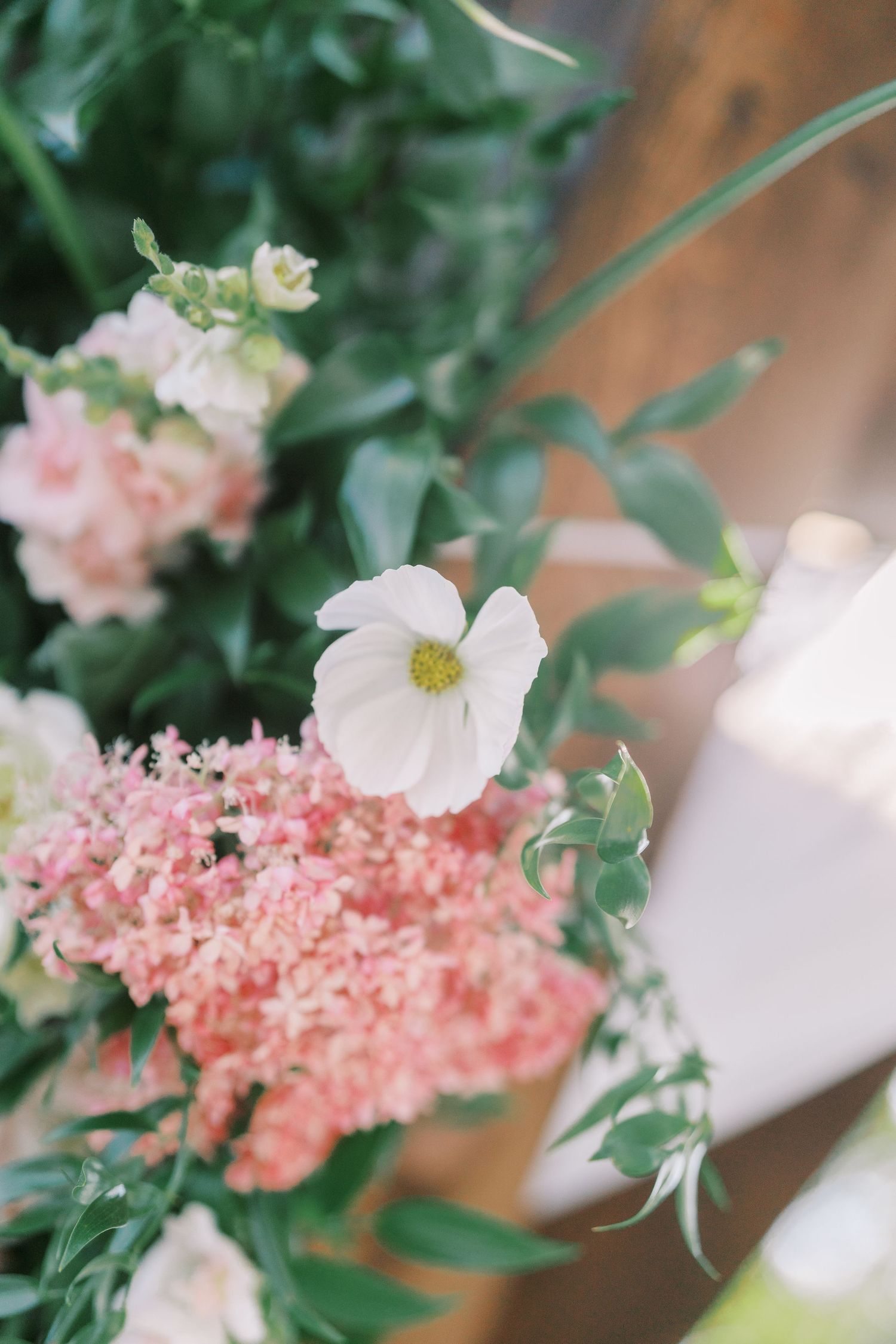 Close-up of delicate pink and white wedding flowers with green foliage.