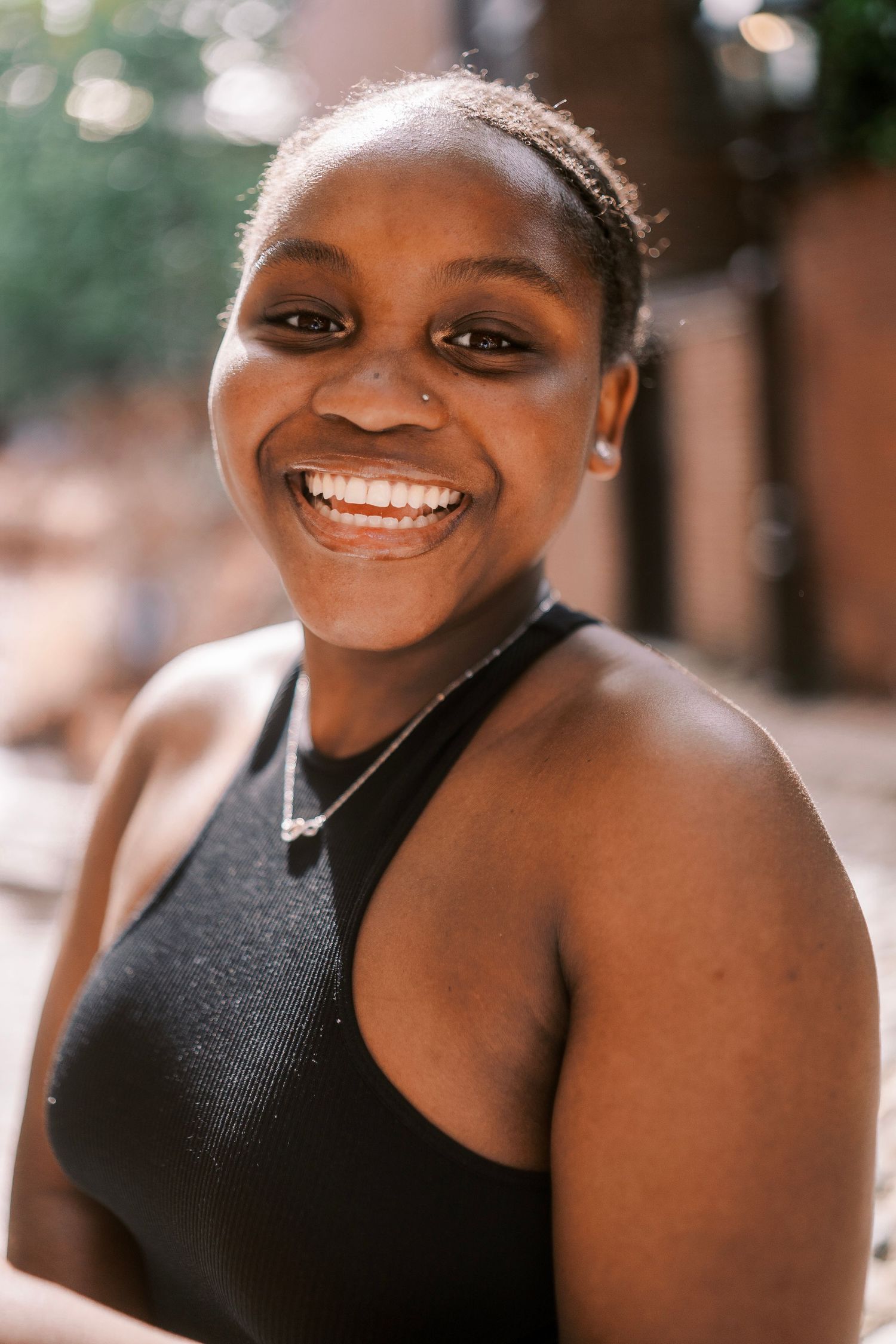 A series of joyful portrait shots showing someone wearing a sleek black dress against a warm natural background.