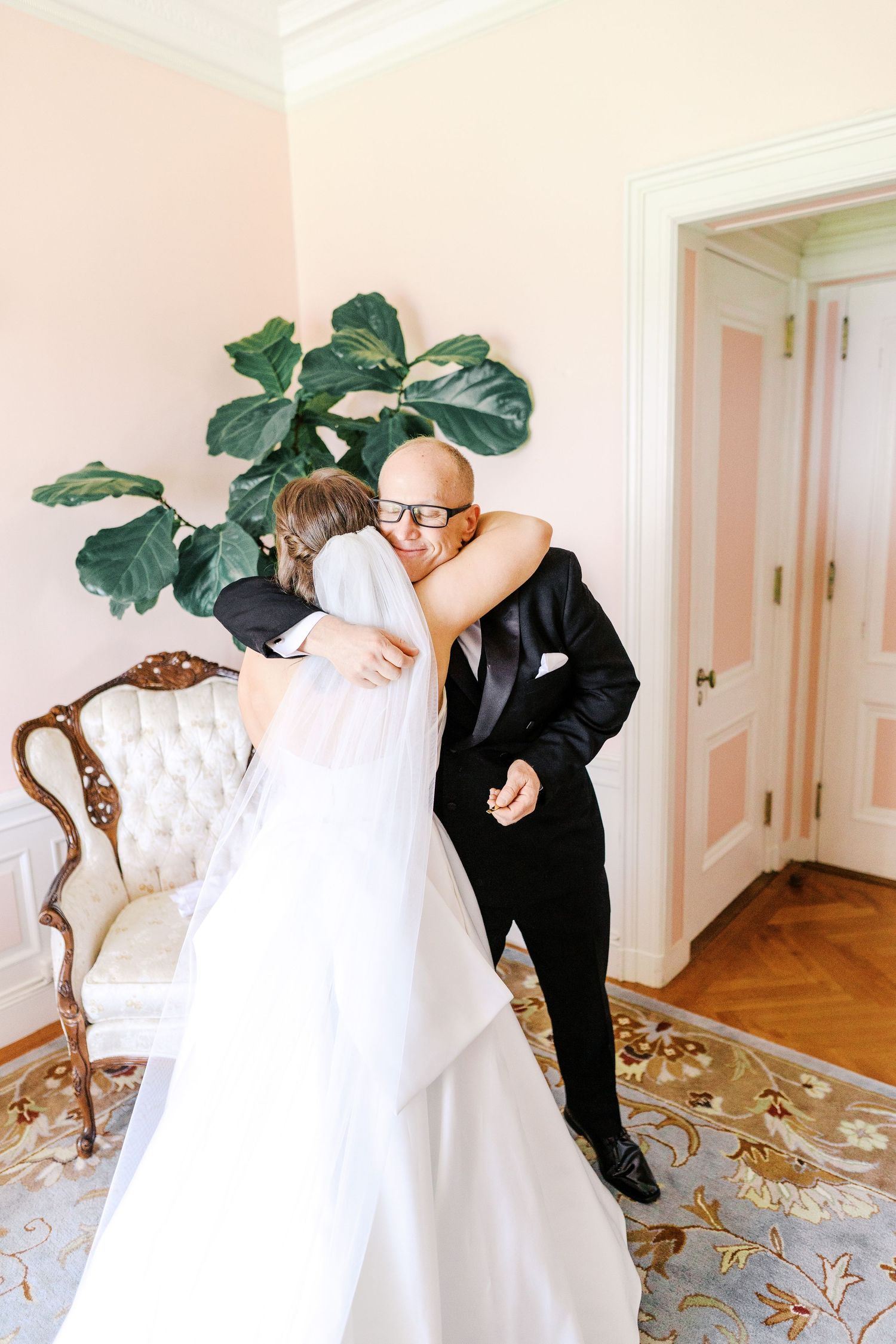 An emotional moment shared between a bride in a white wedding gown and a person in a black suit in an elegant room.