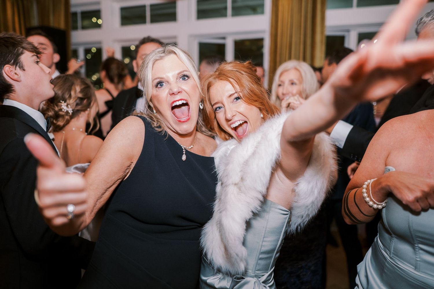 Party guests dancing and laughing together on a crowded dance floor during an energetic celebration.