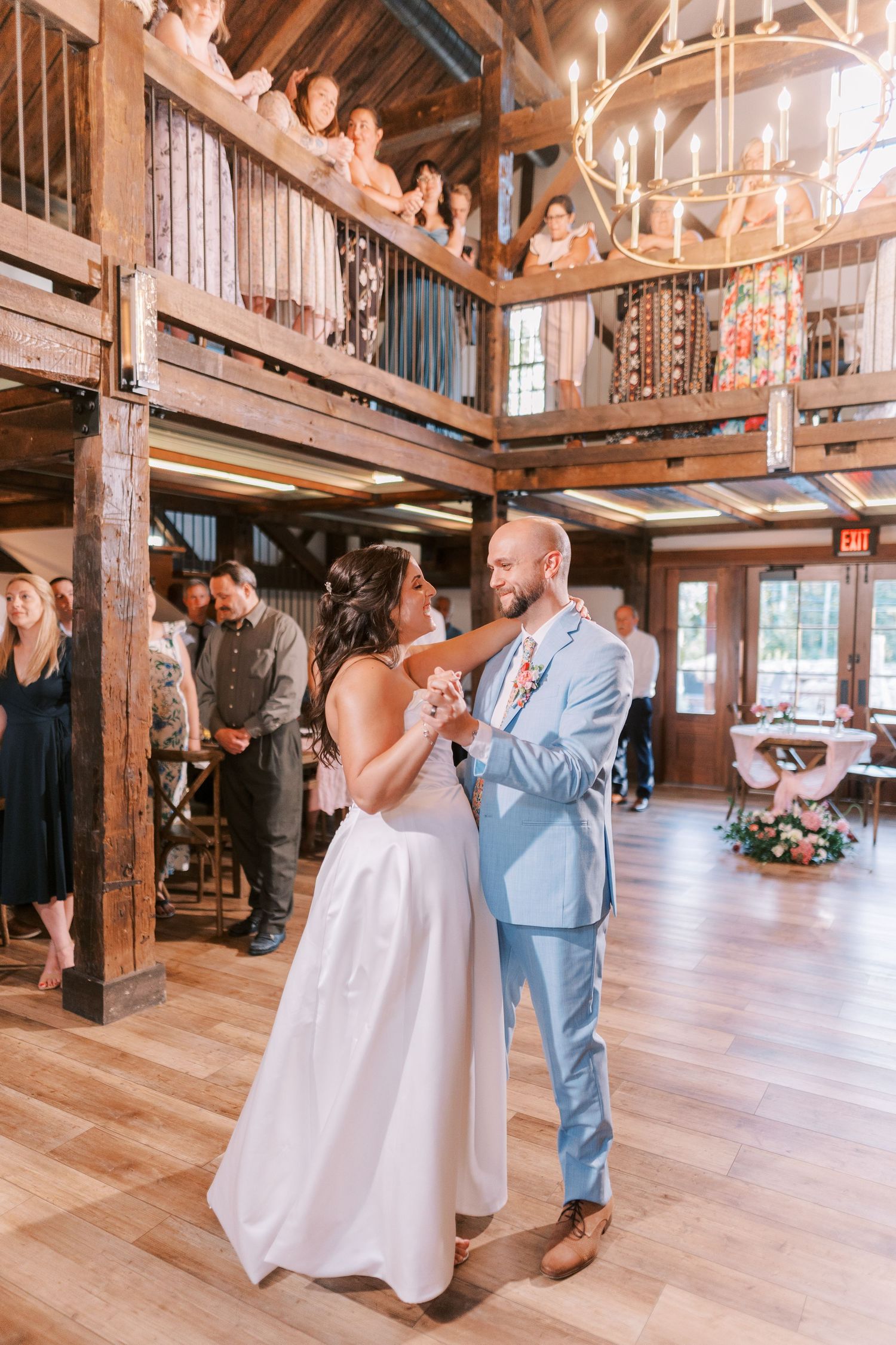 Wedding dance in a rustic barn venue with exposed wooden beams and natural lighting.