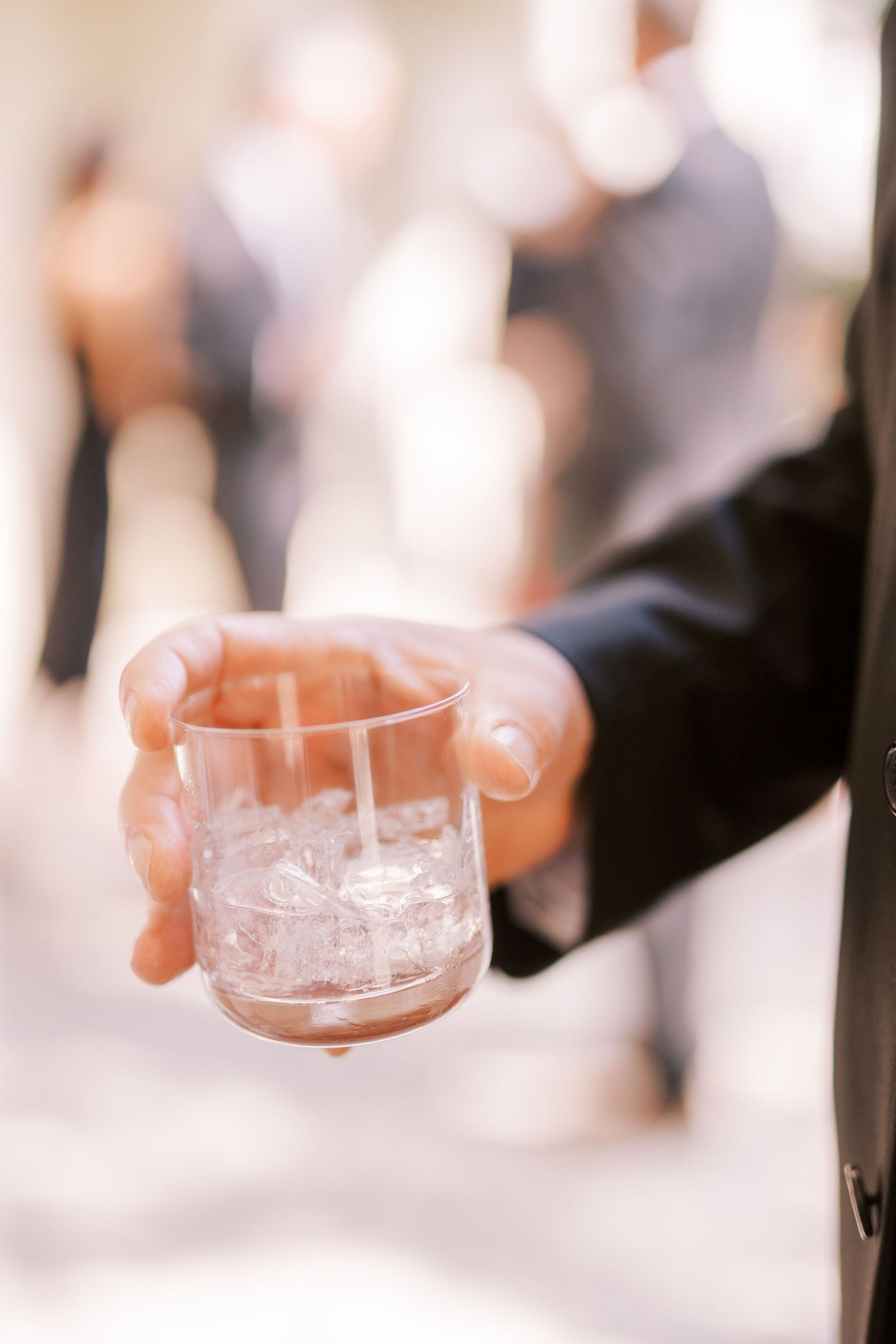Close-up shot of hands clinking crystal glasses with alcohol in a celebration toast at an elegant event.