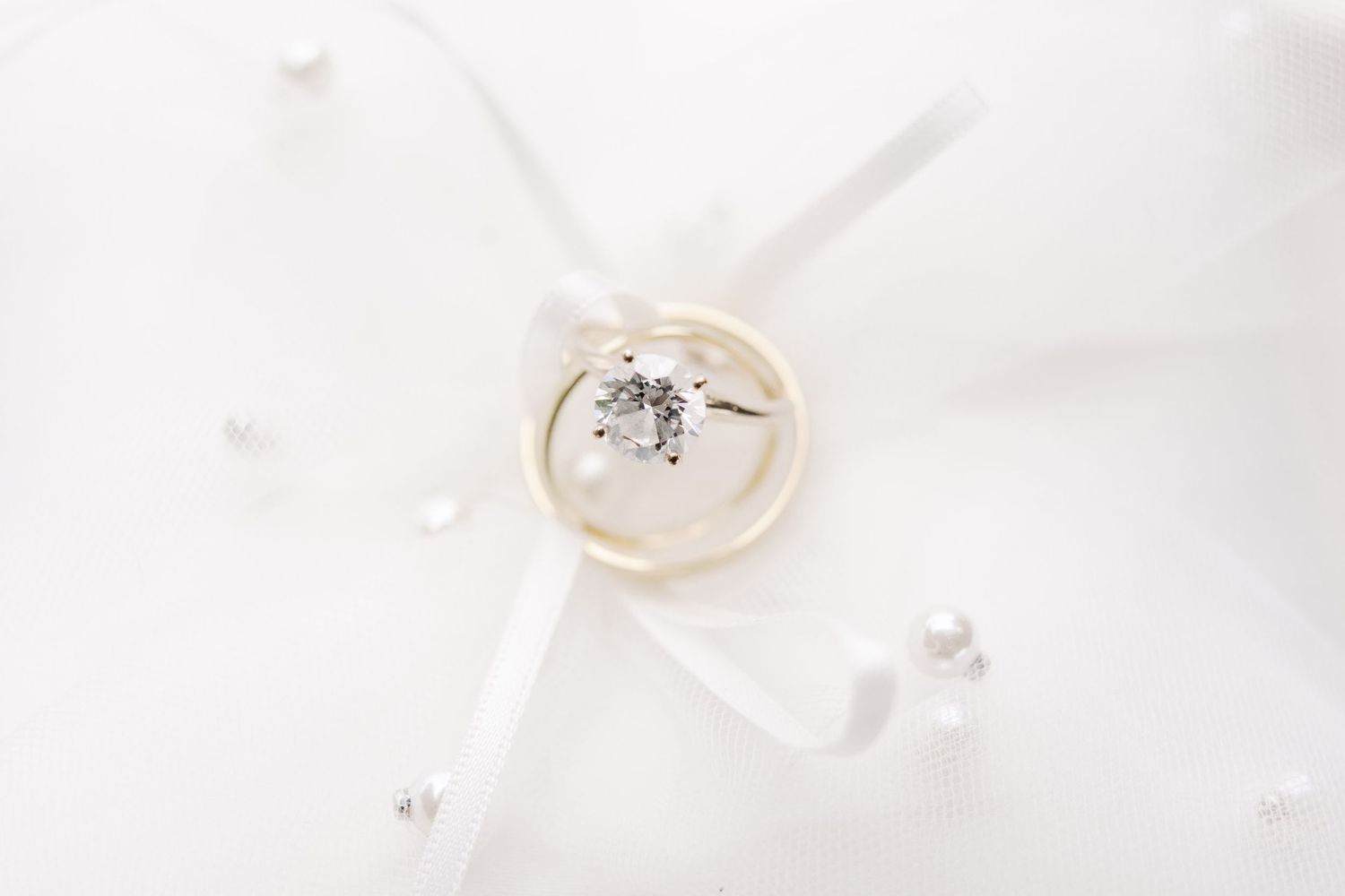 A sparkling diamond engagement ring displayed on white fabric.