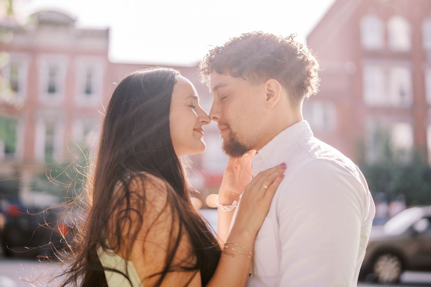 A romantic moment shared between a couple in front of brick buildings during golden hour.
