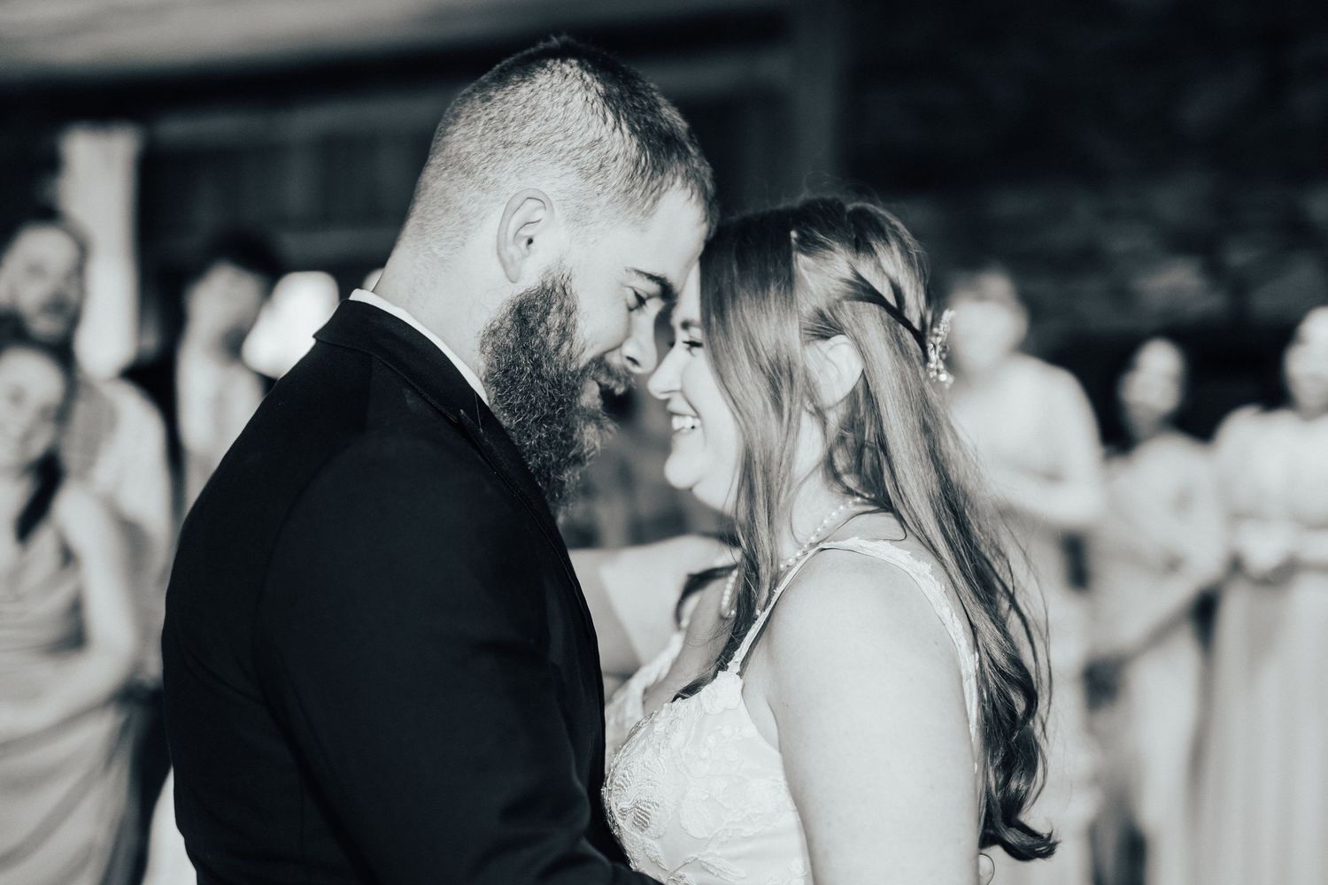 A black and white candid moment of a couple sharing their first dance at their wedding reception.