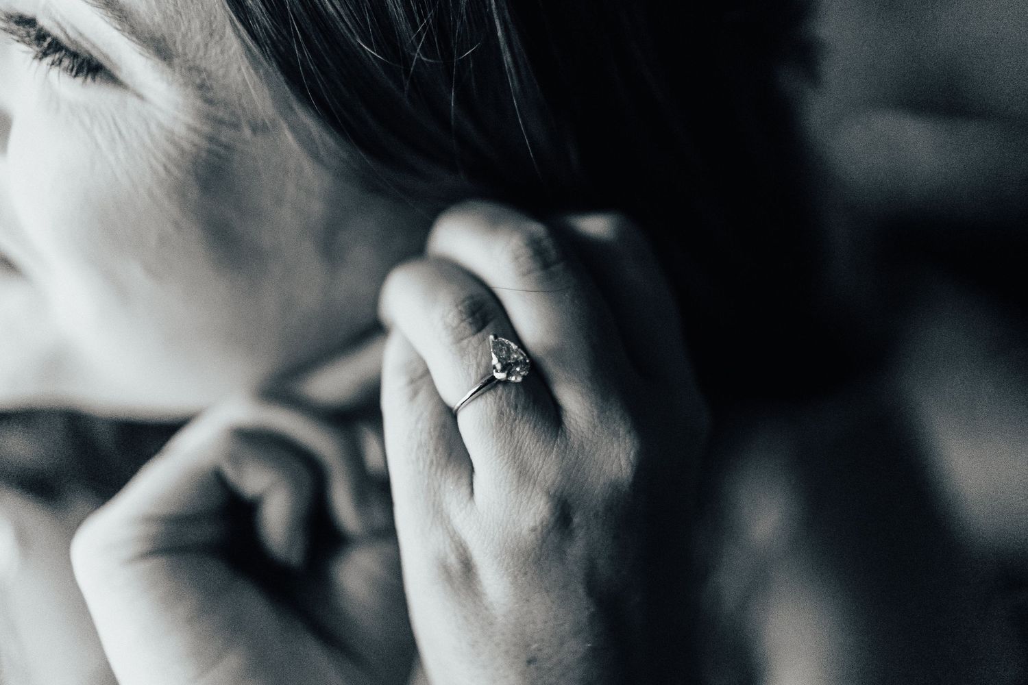 Close up black and white photo of an engagement ring on a hand.