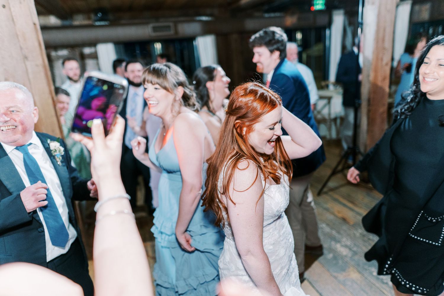 Wedding reception dance party with guests in blue dresses enjoying celebration.