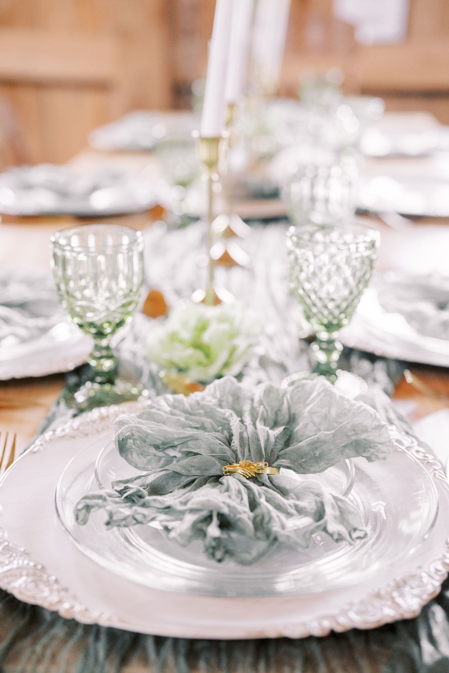 Elegant place settings feature white plates with soft gray napkins and vintage green glassware on a formal dining table.