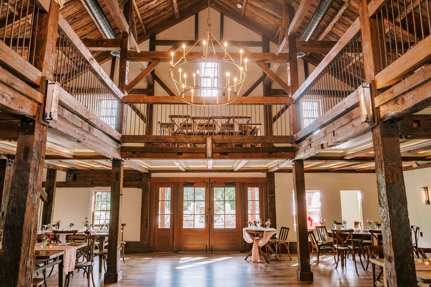Rustic barn wedding venue interior with exposed beams and wooden balcony.