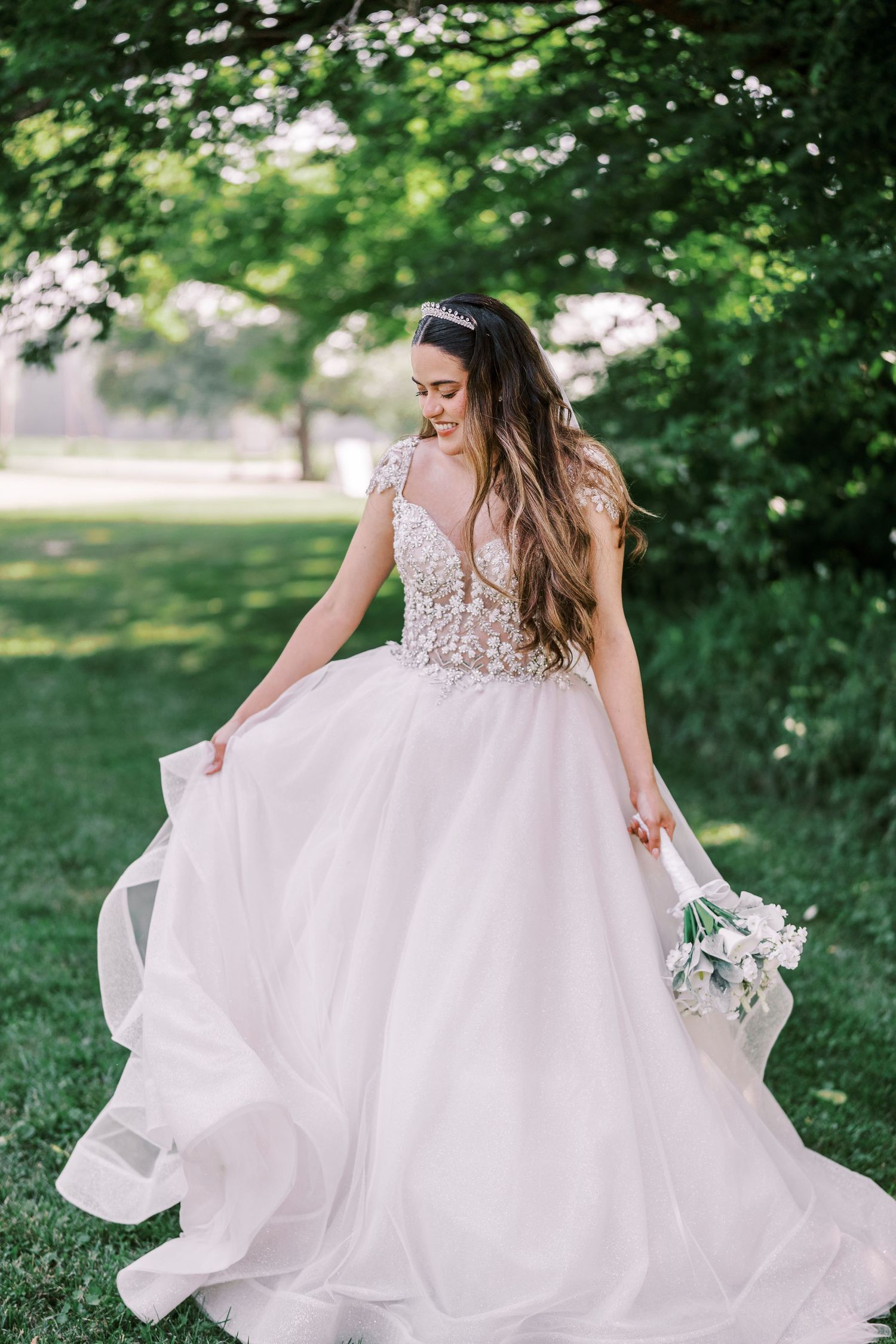 Ethereal wedding gown with delicate beaded bodice and flowing tulle skirt twirls in a garden setting.