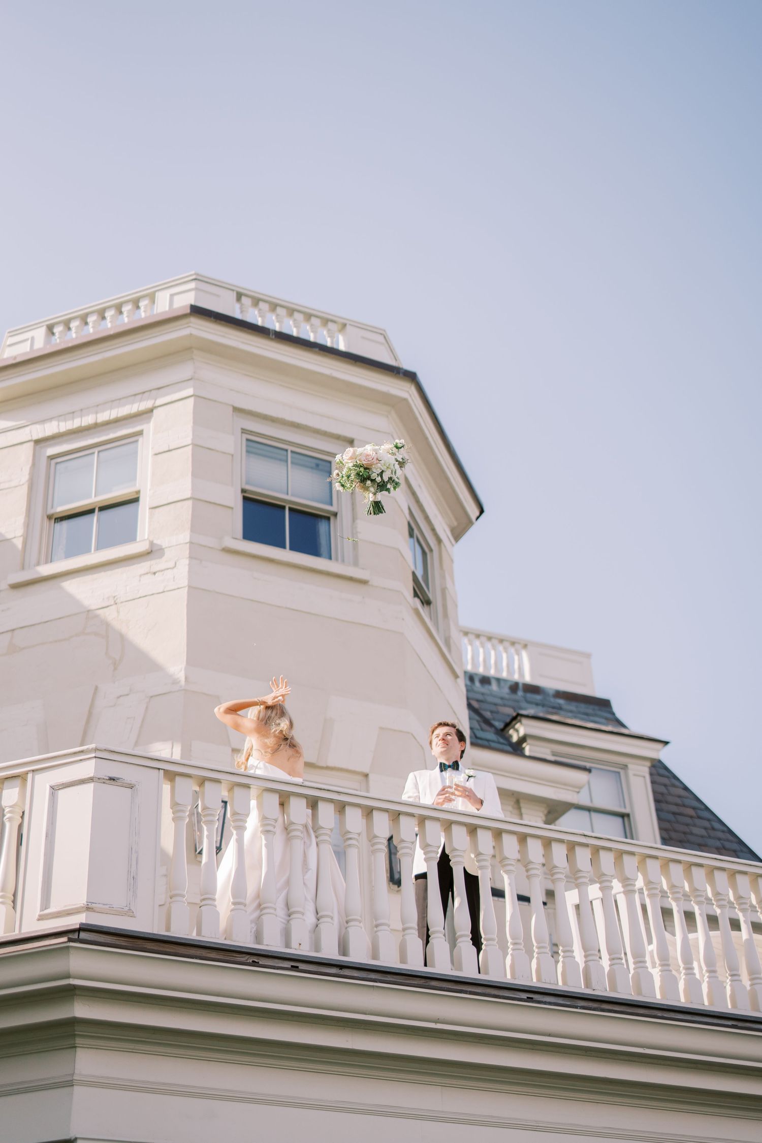 White coastal mansion with ornate balcony railings and large windows overlooking beachfront property.