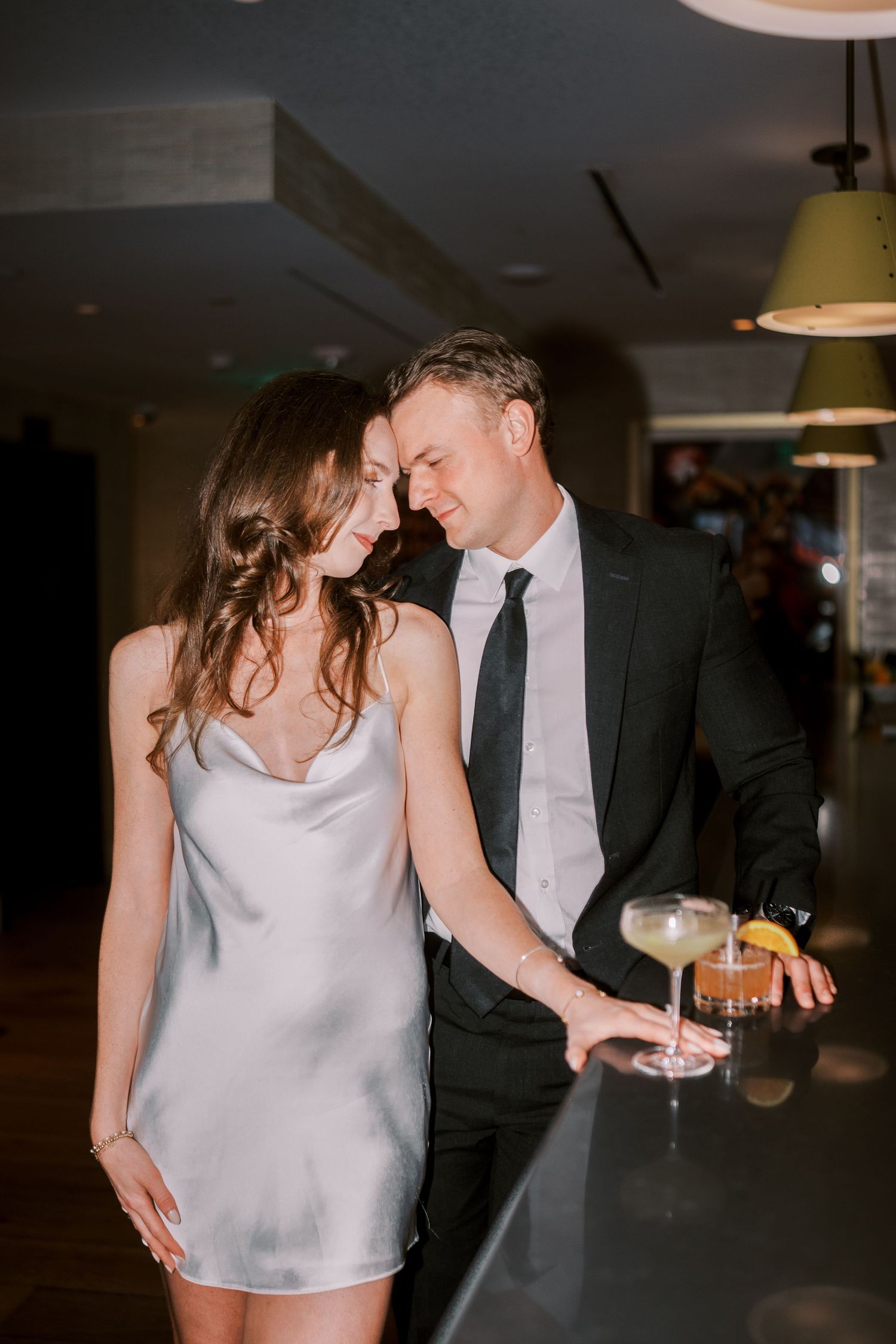 A couple shares an intimate dance together in a dimly lit indoor venue during what appears to be a wedding reception.