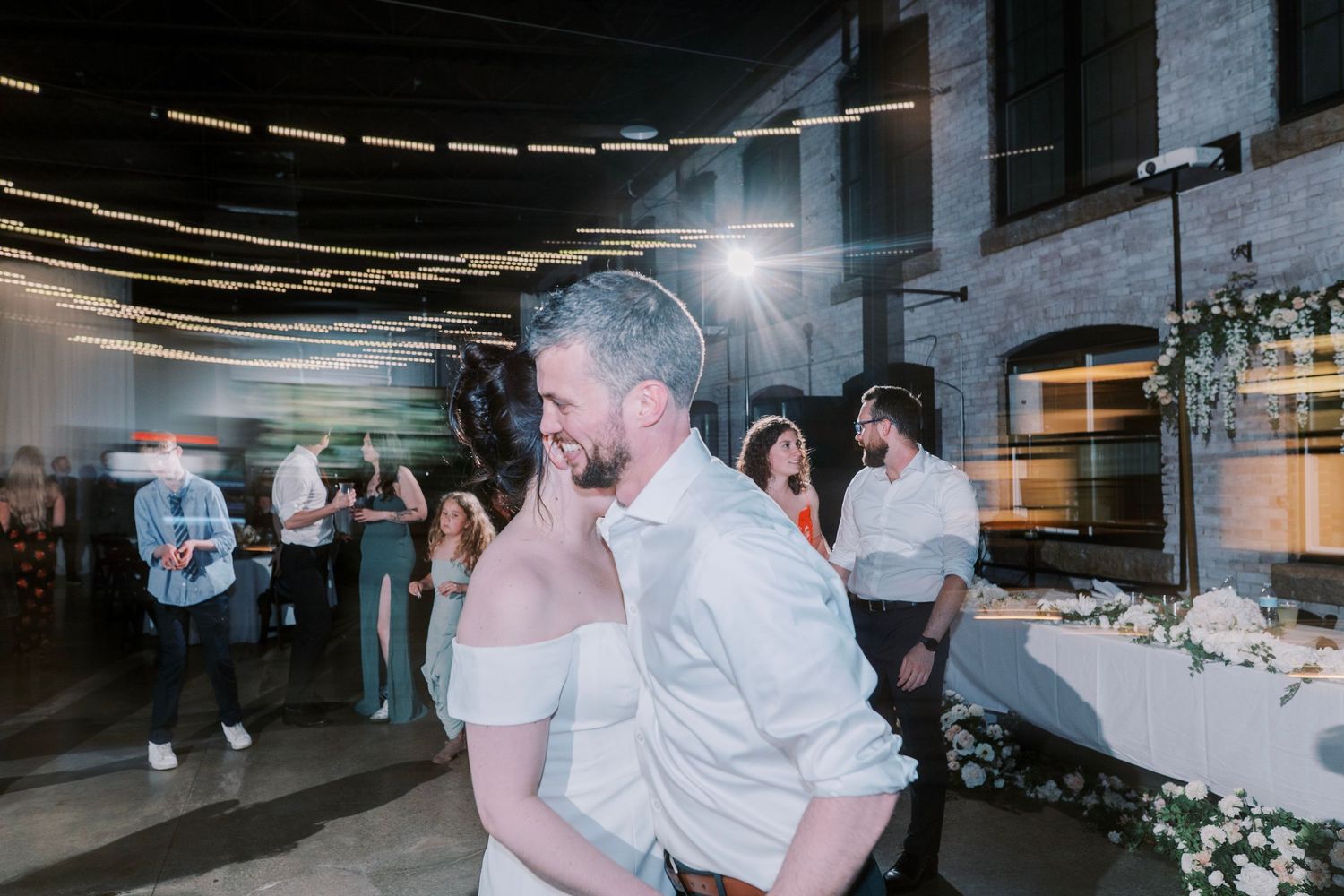 Reception dance floor moment with string lights and industrial venue setting.