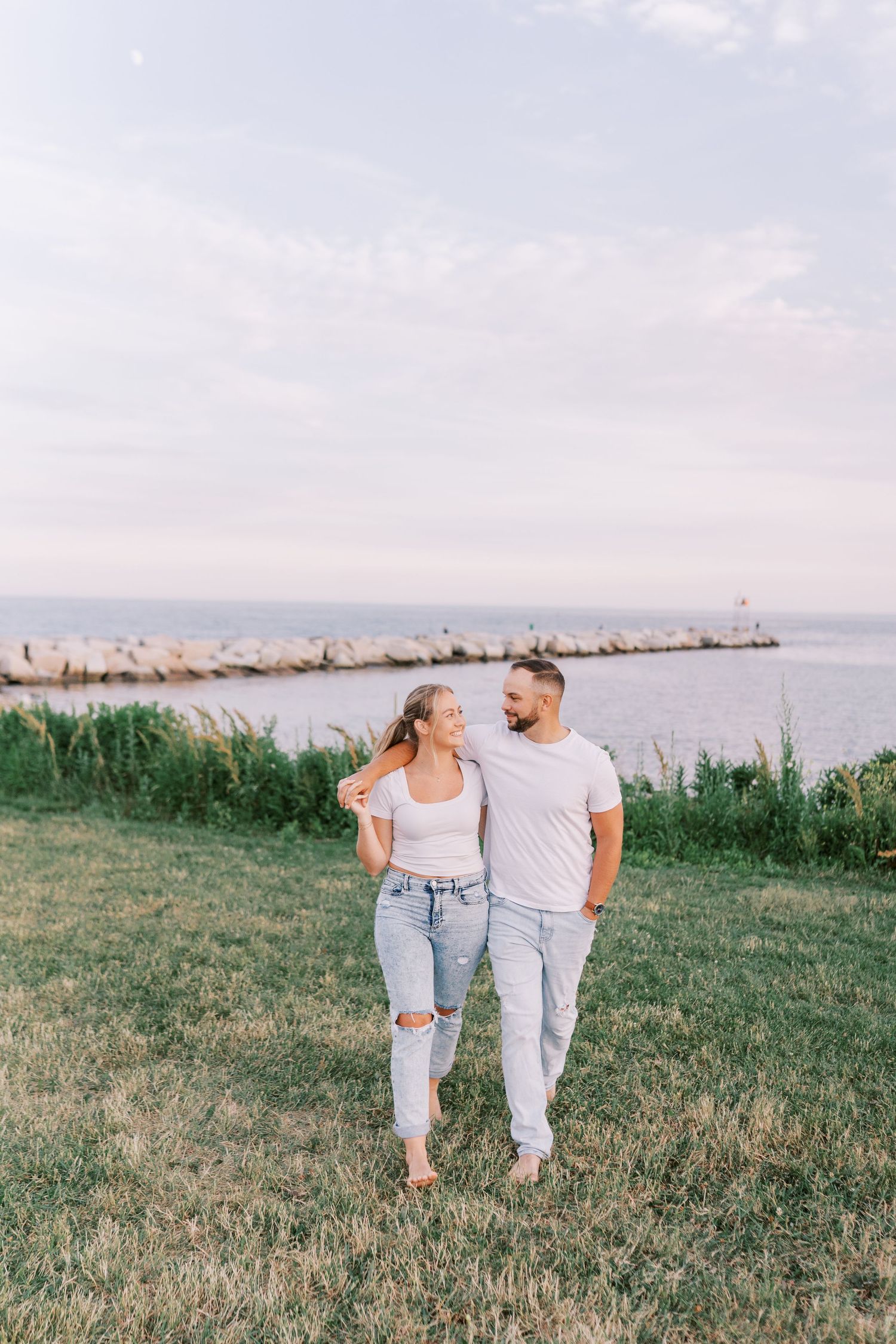 Couple walking together along coastal path in casual matching outfits.