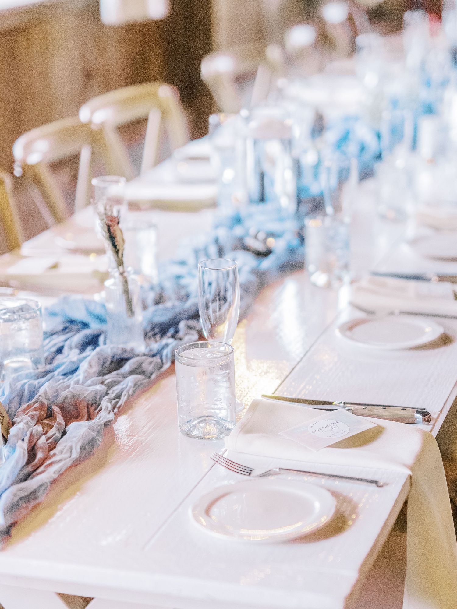 An elegant wedding table setting with light blue table runners and white place settings.