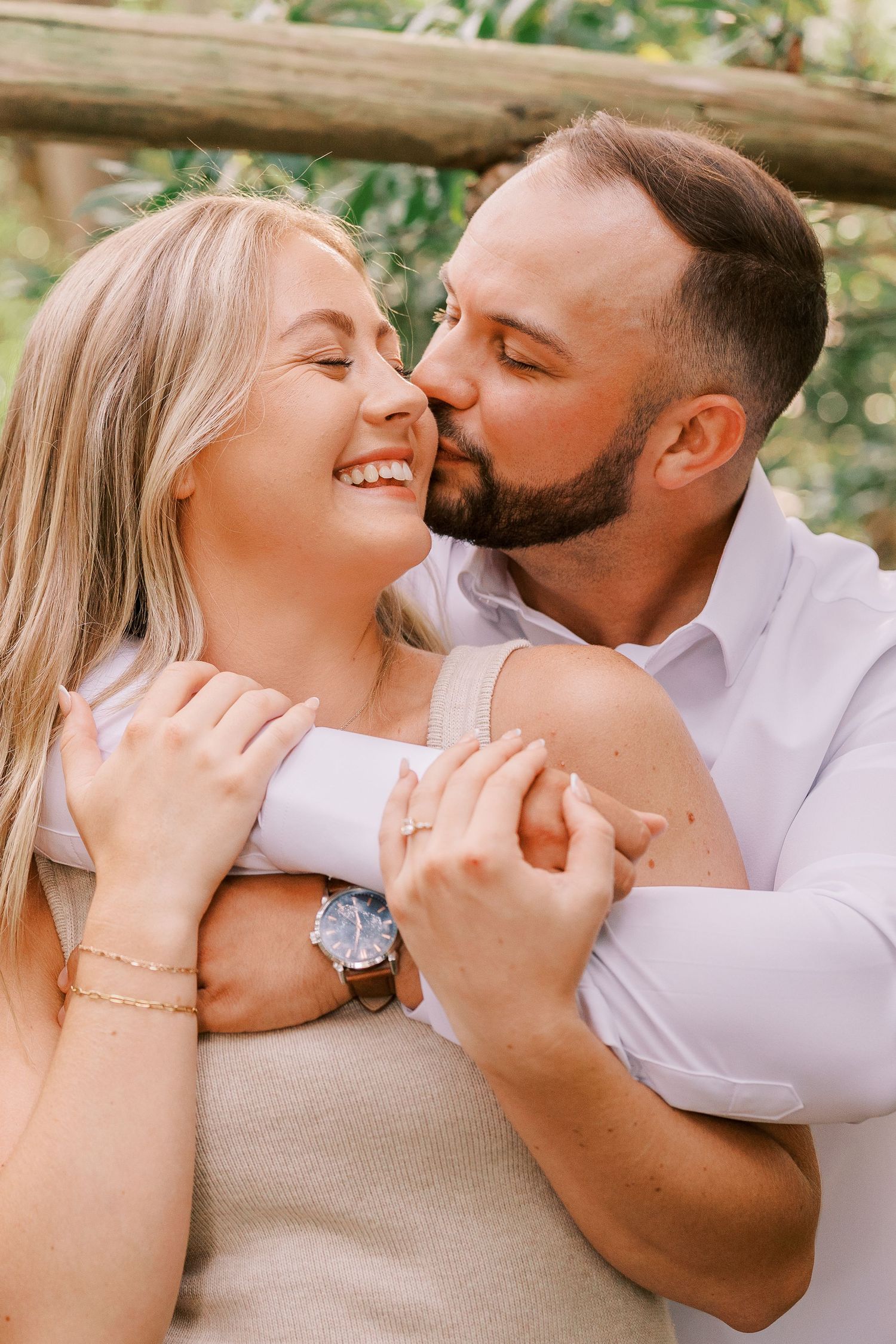 A romantic outdoor portrait of a couple embracing and sharing a tender moment in natural lighting.
