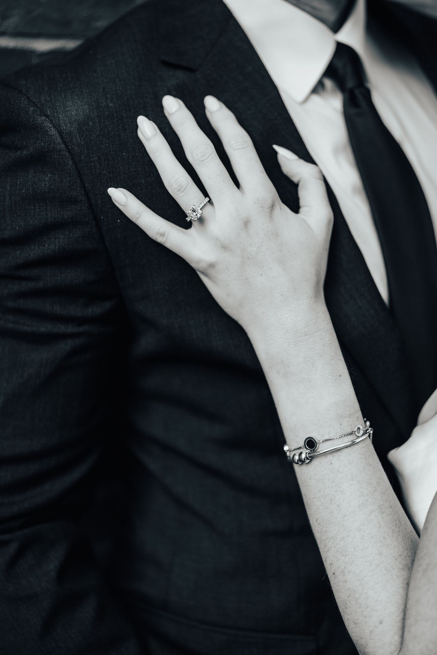 Close-up series of black and white photos showing hands wearing delicate rings against formal attire.