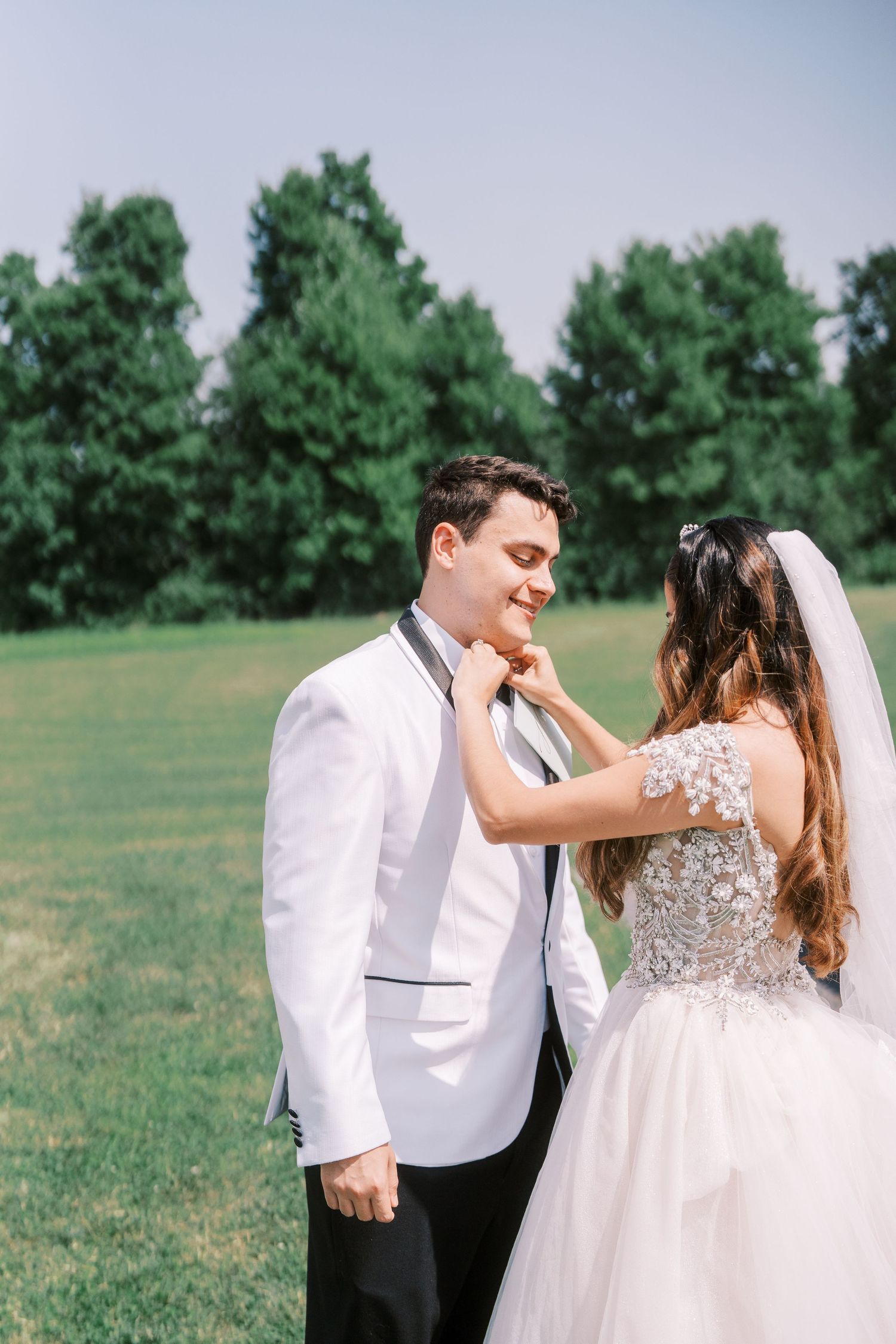 A series of romantic wedding photos showing newlyweds sharing tender moments in a green field on their special day.