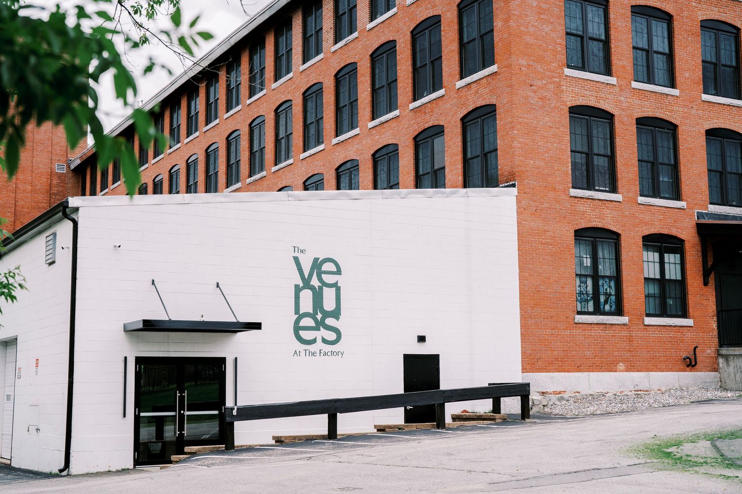 Red brick factory building exterior with white facade entrance and modern signage.