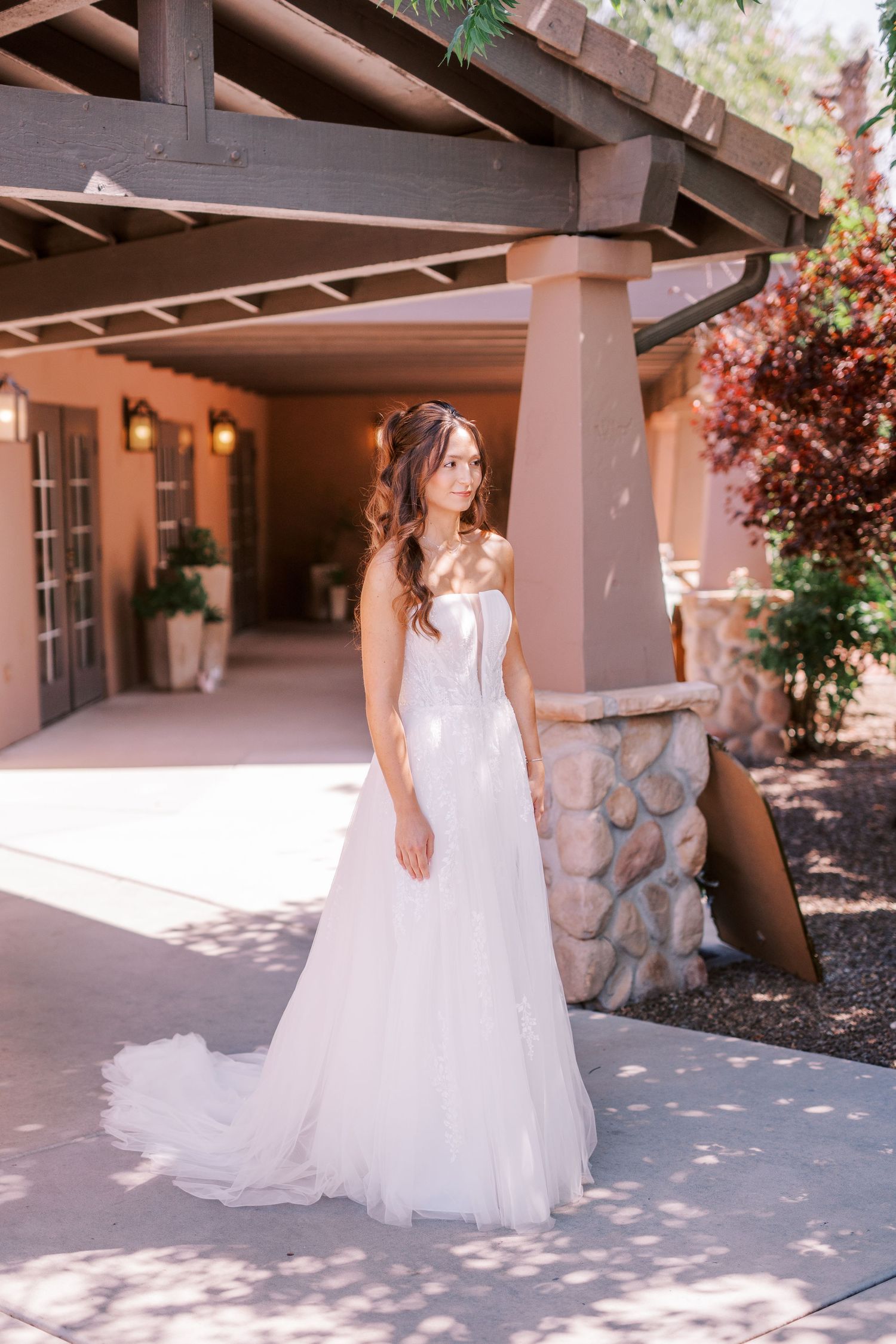 A flowing white wedding dress train elegantly trails across a shaded outdoor patio area.
