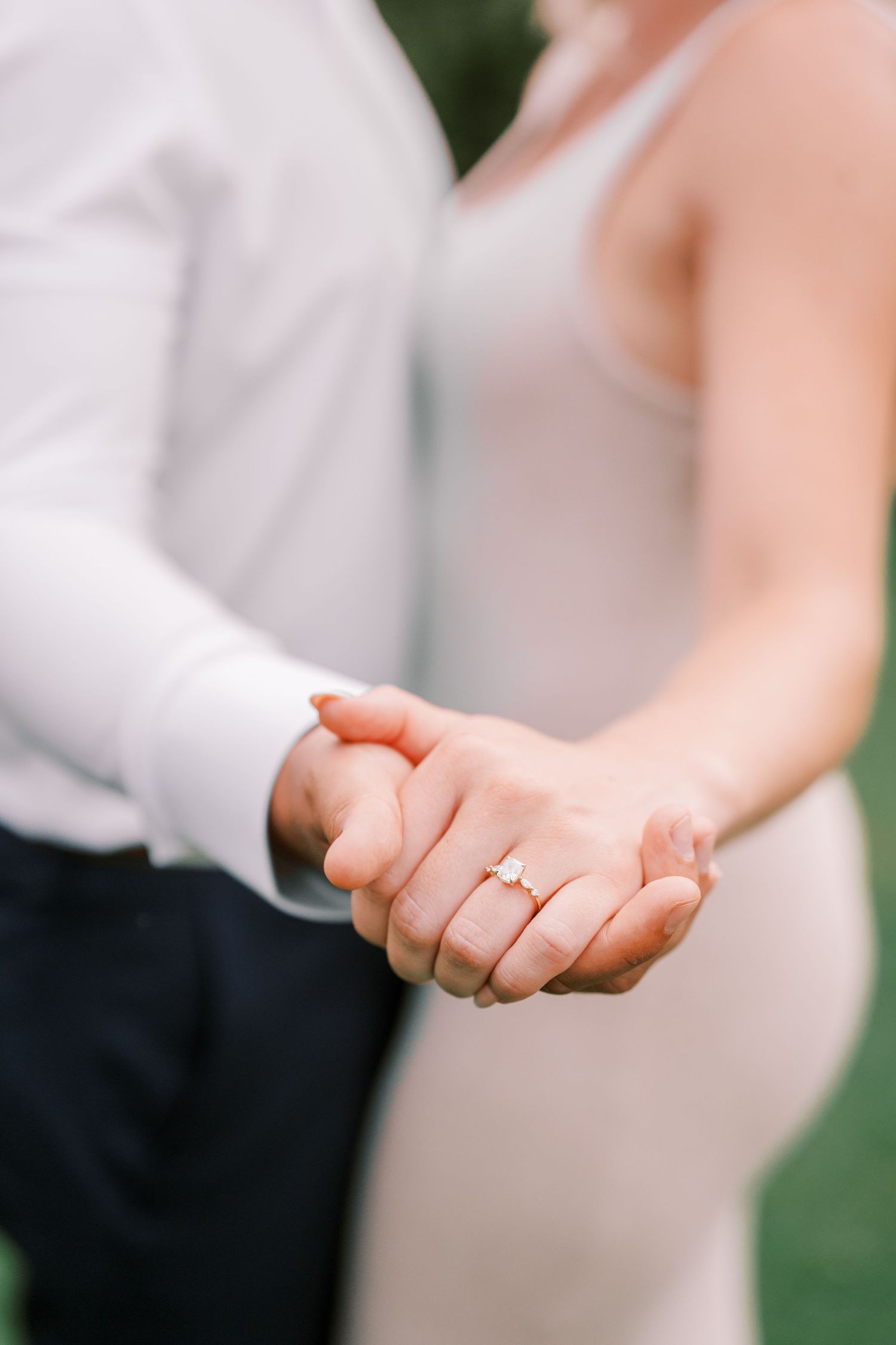 Close-up of hands clasped together showing engagement ring detail.