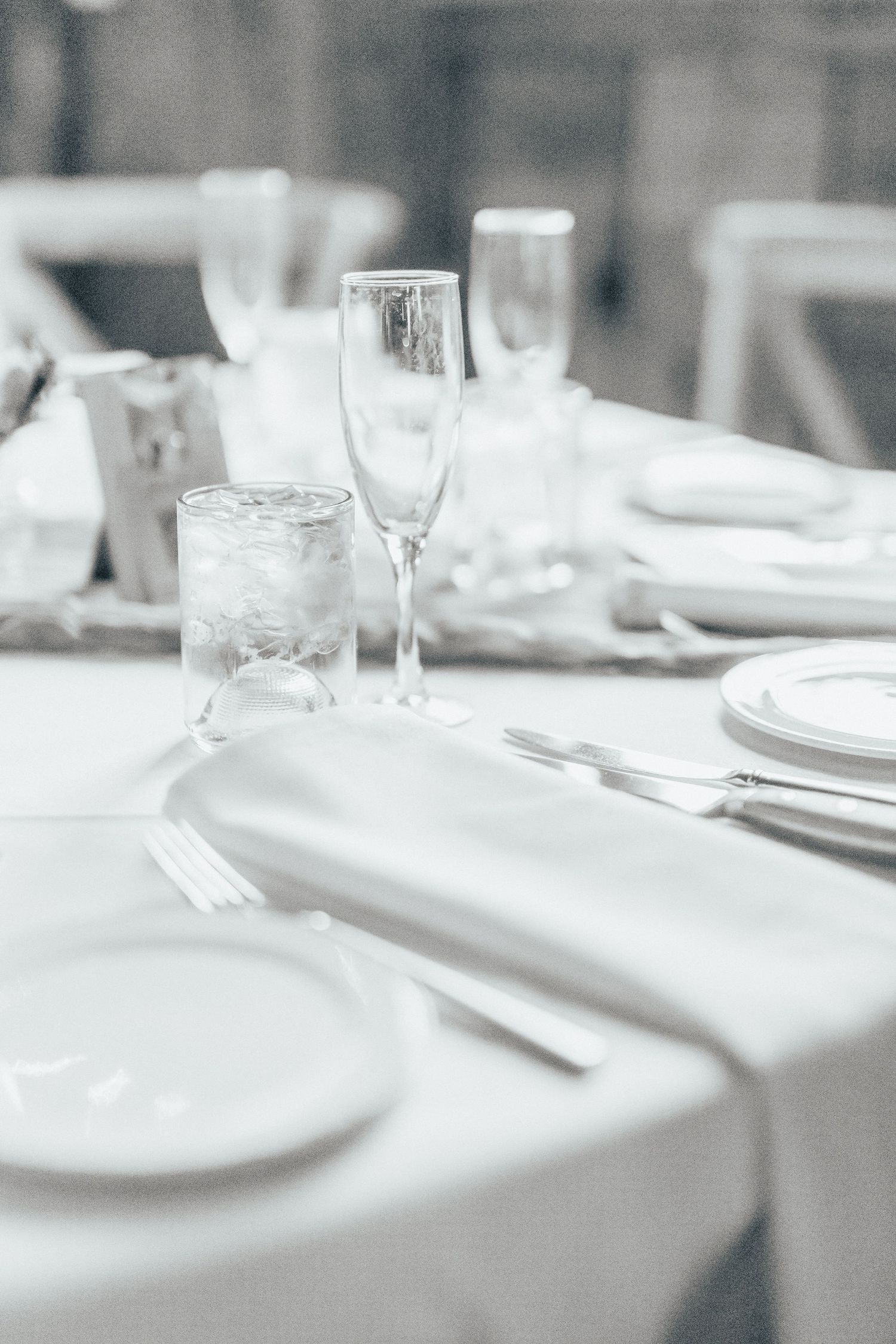 Elegant table setting with white linens, crystal glasses and formal dinnerware at an upscale event.