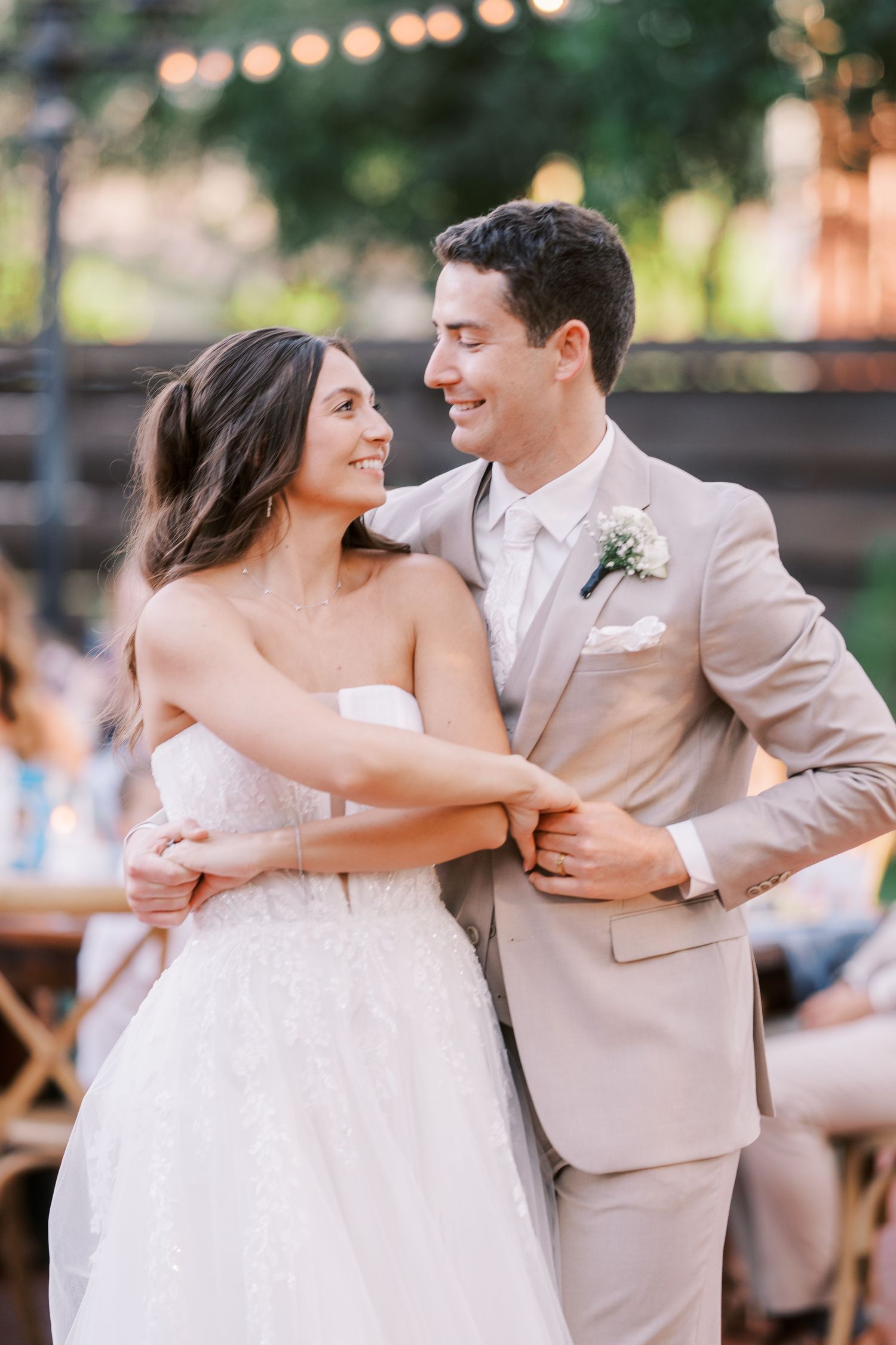 A happy couple sharing an intimate moment at their wedding, the bride in white and groom in beige.