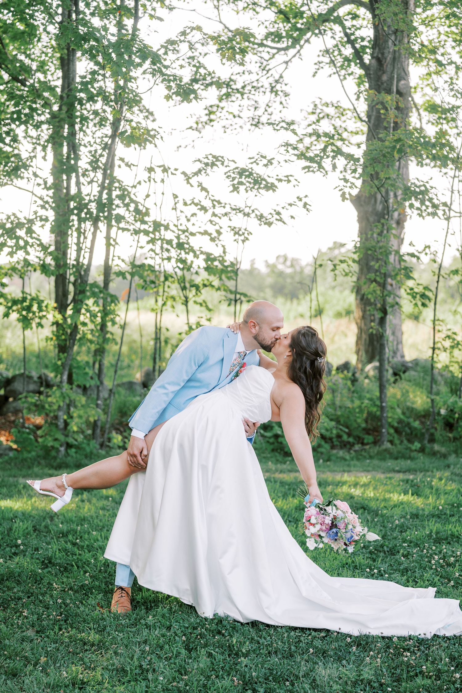 Romantic wedding pose captured in a sunlit garden with flowing white dress.
