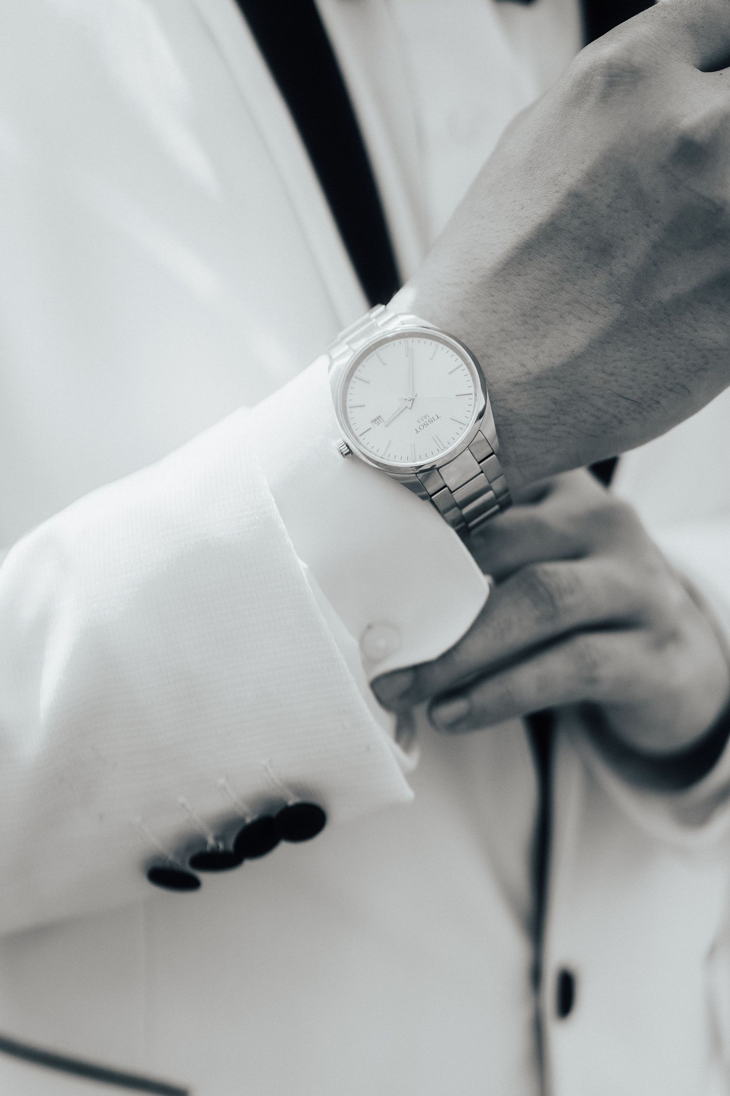 Close-up of a silver wristwatch on someone wearing a white blazer with style and elegance.